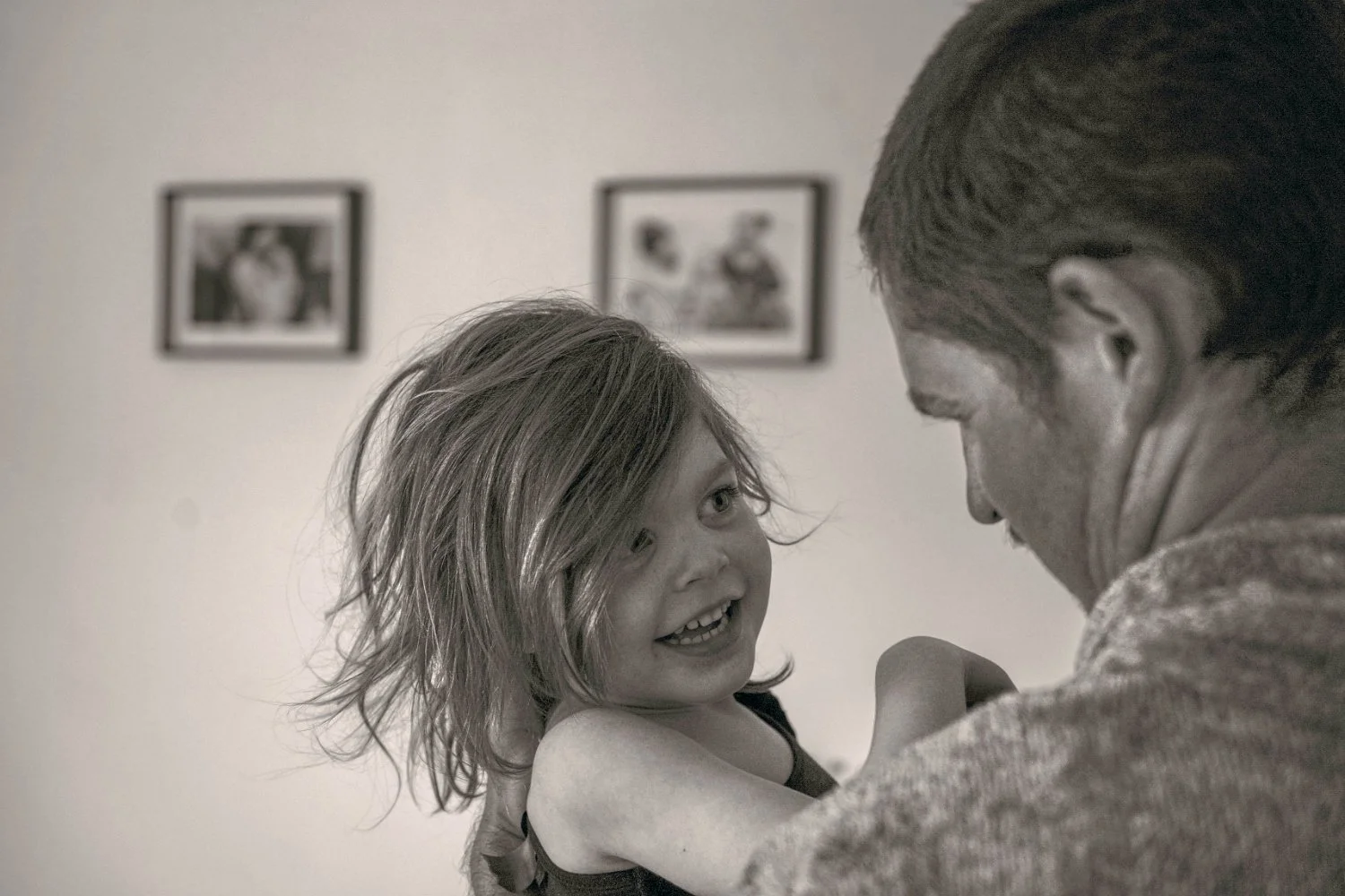 A young girl with messy hair smiles at her dad