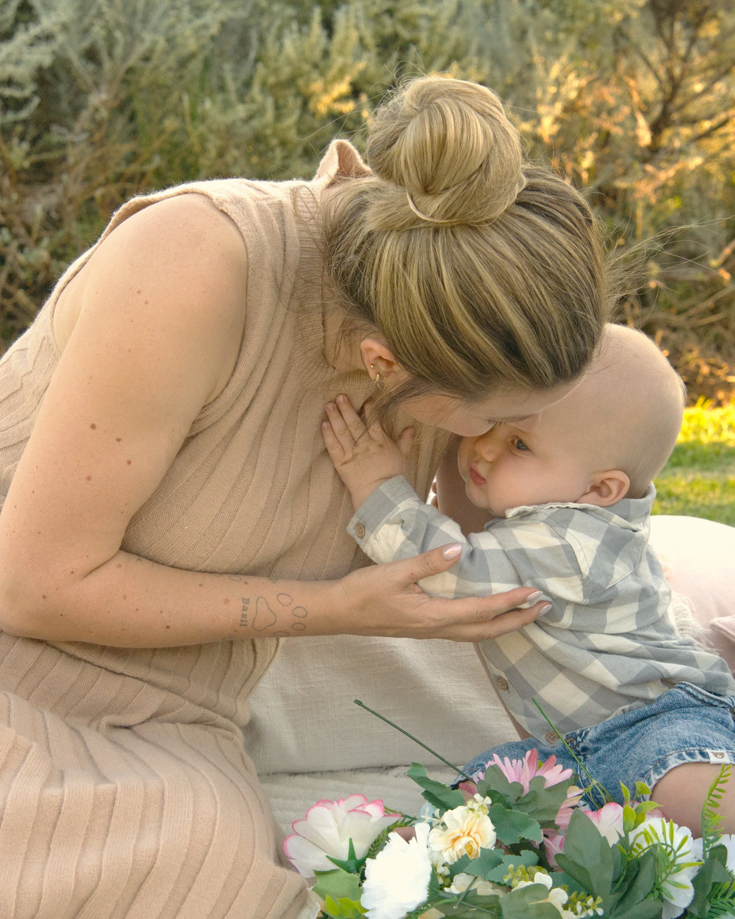 A blonde boy, toddler, reaches for his mother