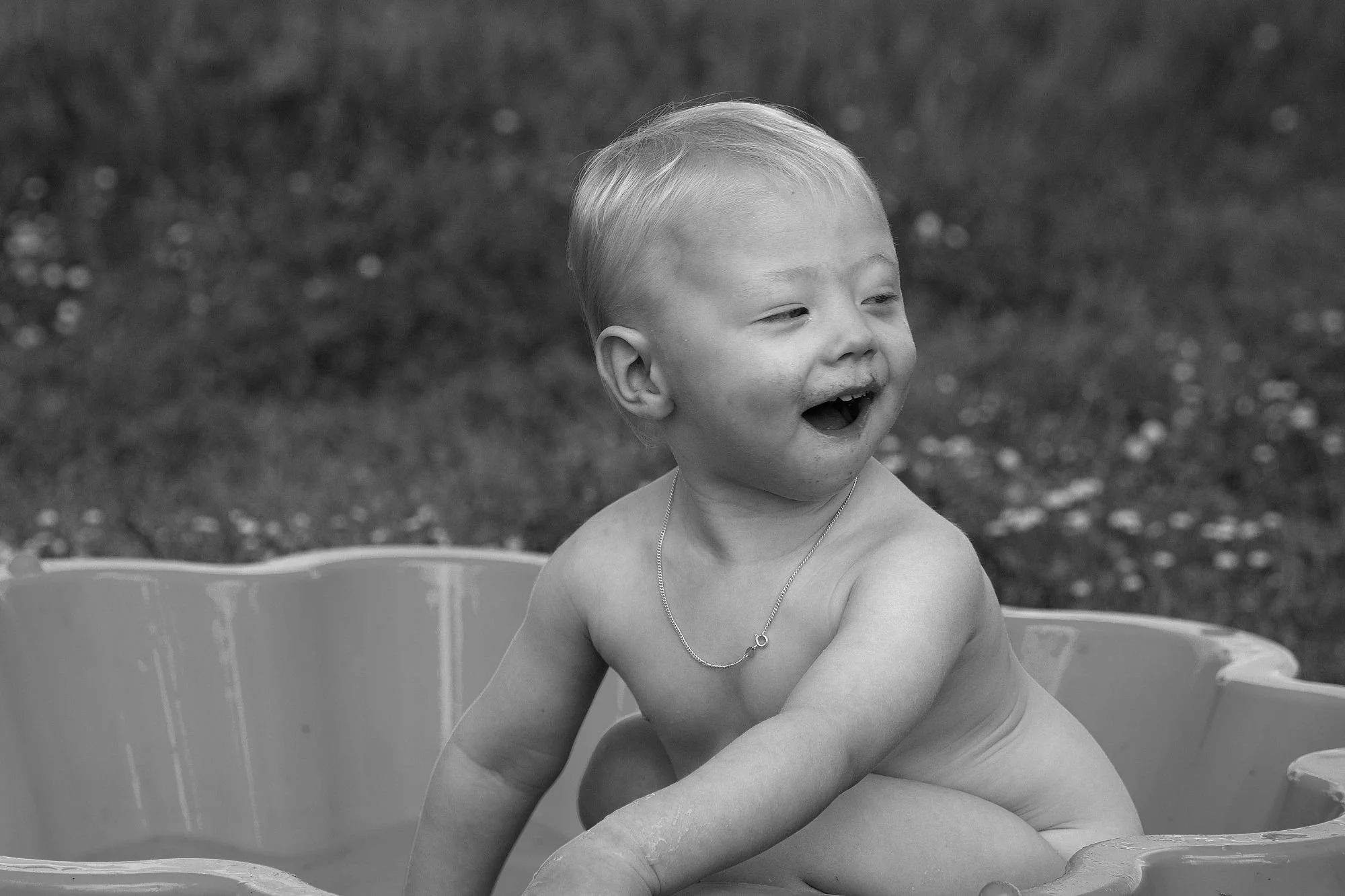 A black and white photograph of a young boy playing in a shell pool