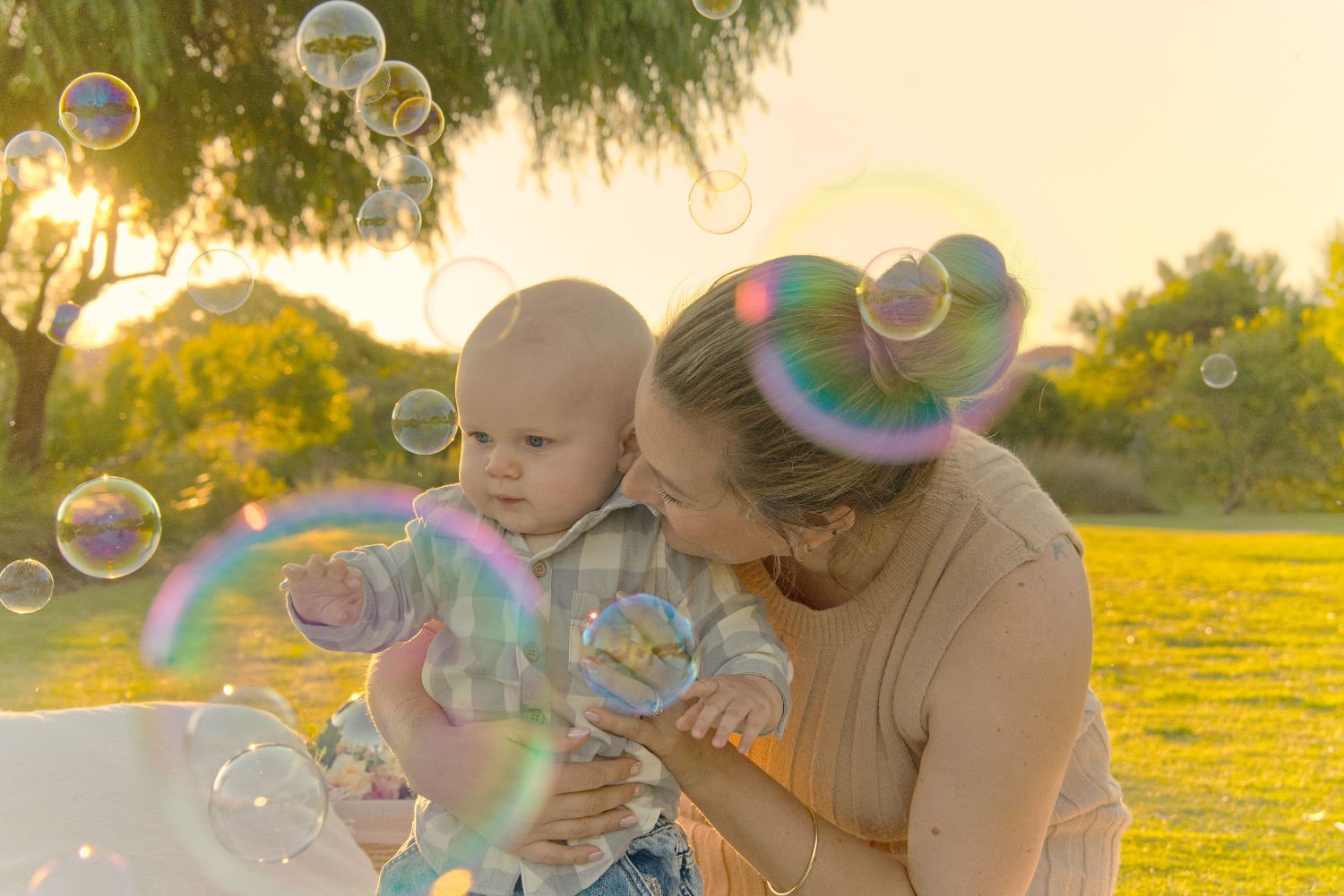A mother smiles at her child as they play in bubbles