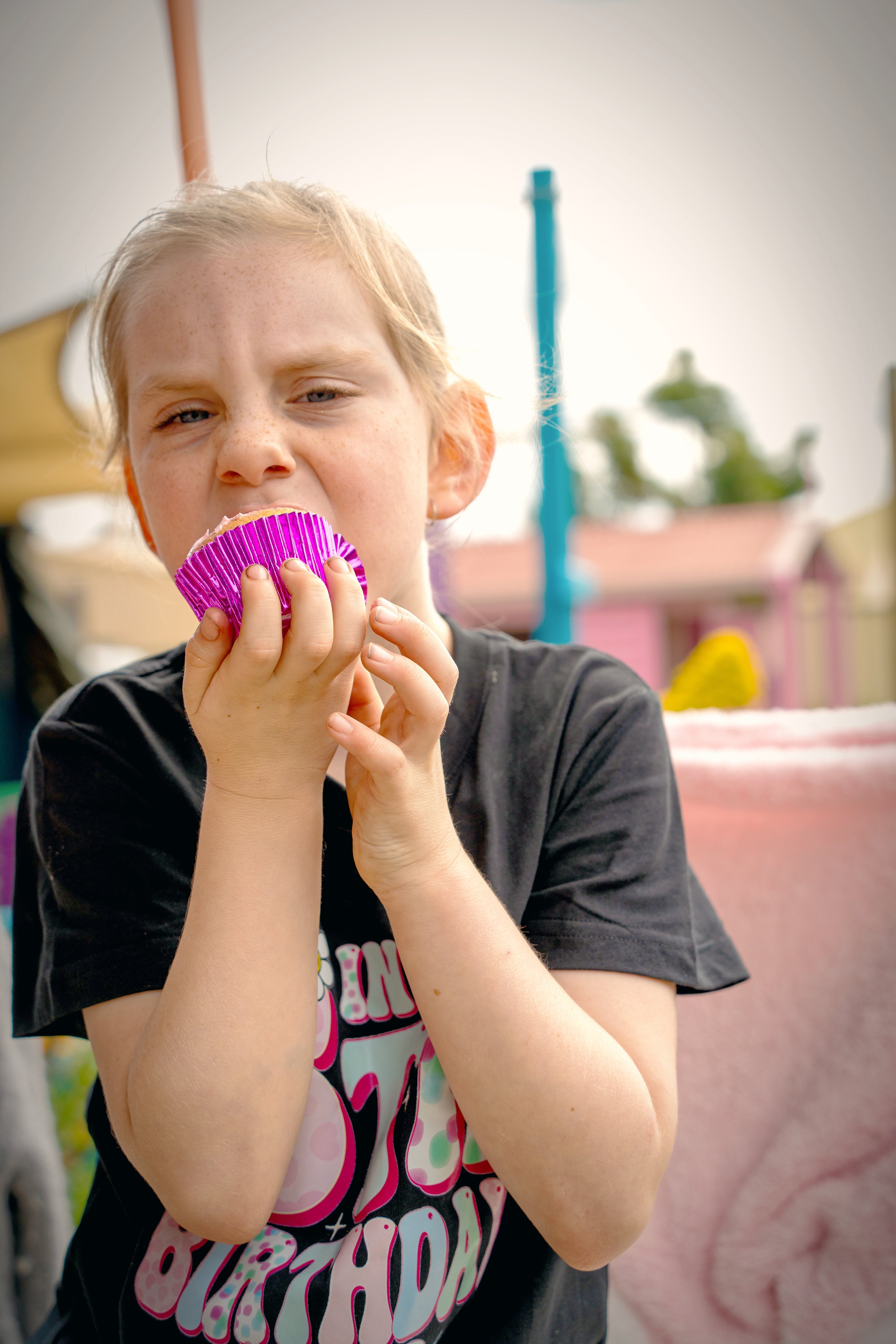 A young girl eats a cupcake at a birthday party