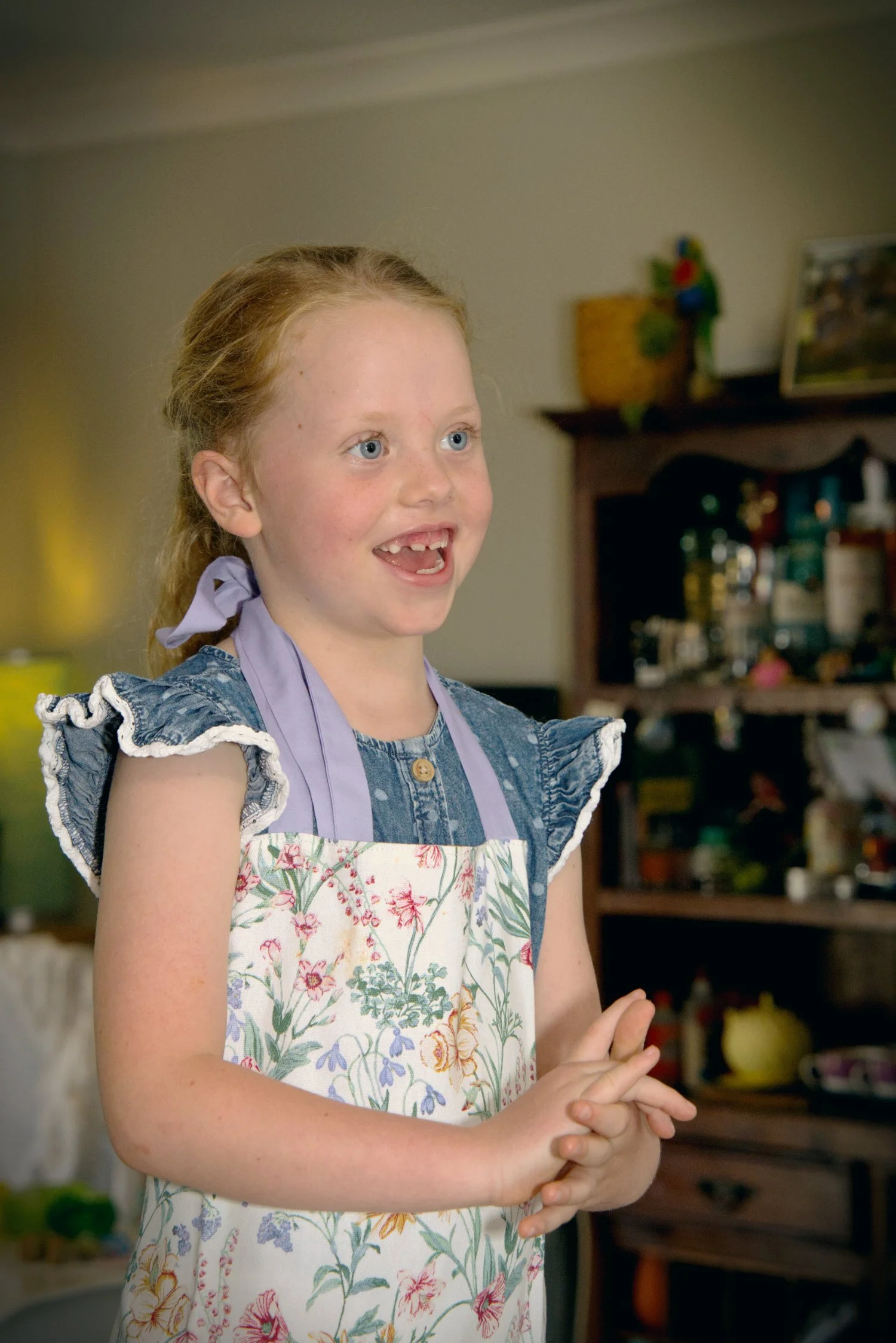 A red headed girl wearing an apron smiles in this art portrait