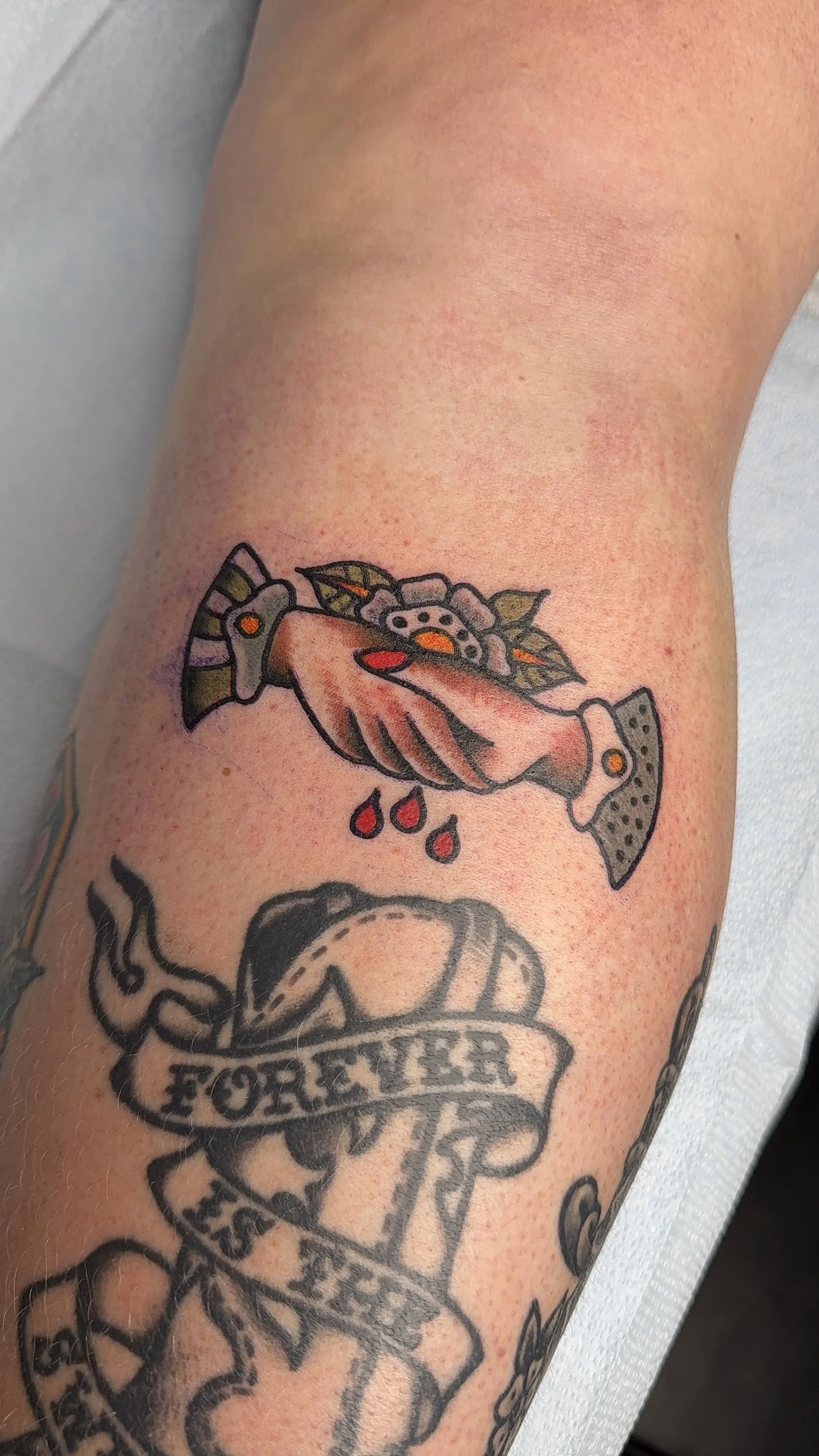 Tattoo oft hands shaking blood drops on an arm with other tattoos around. Tattoo inspired by Hayley Williams album Ego Death at a Bachelorette Party. 