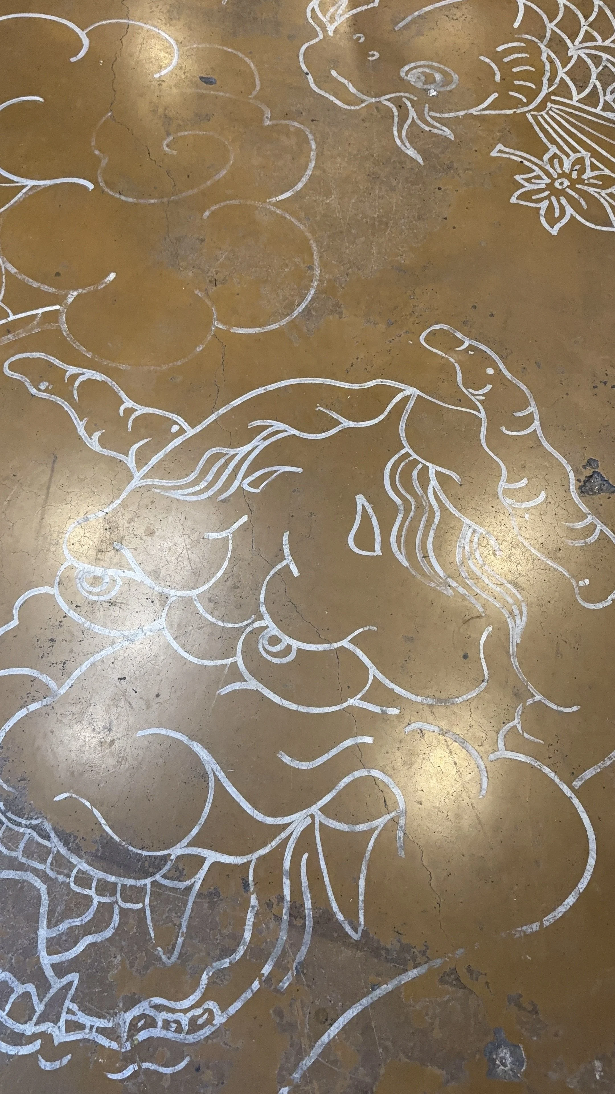Decorative floor with white chalk outline of a floral design on a brown surface.