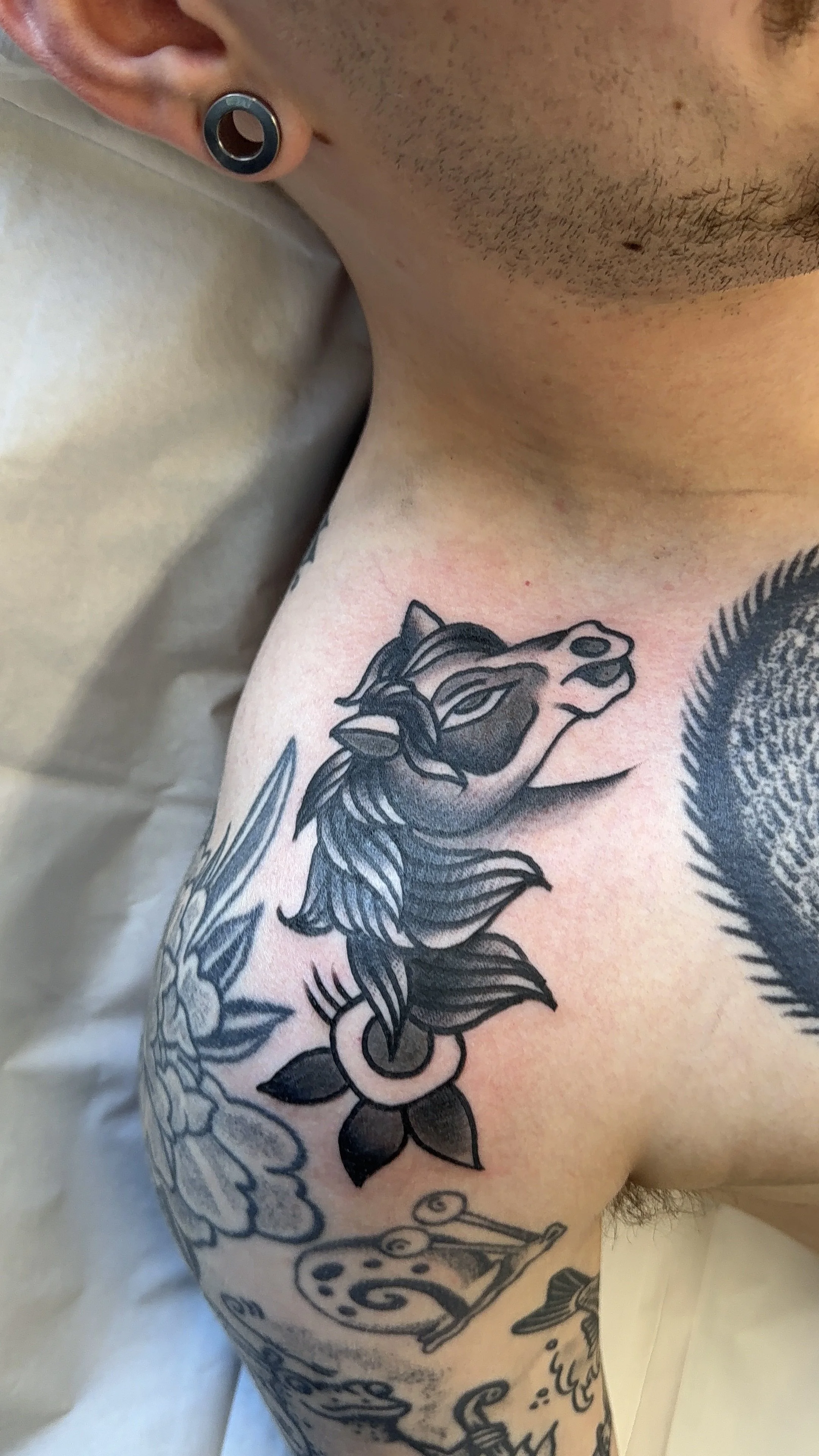 Close-up of a person's upper arm with a black and gray tattoo of a horse with a flowing mane and detailed shading, visible across the shoulder and upper arm.