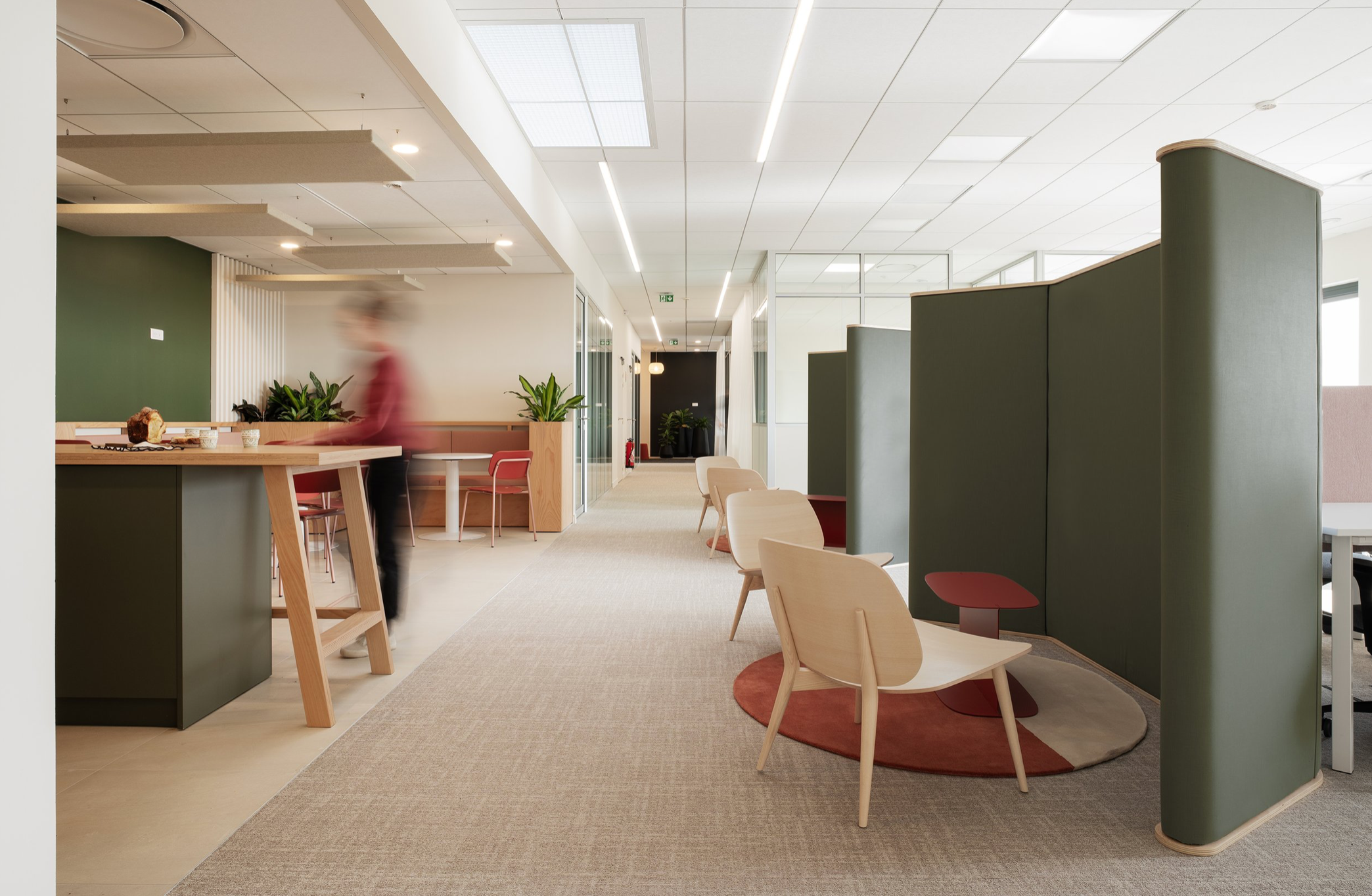 Espace convivial d'un siège social d'une entreprise. architecte d'intérieur tertiaire lyon. Cuisine sur mesure et espace de pause. moquette au sol, carrelage beige, mobilier chaleureux, séparateur acoustique côté bureaux.