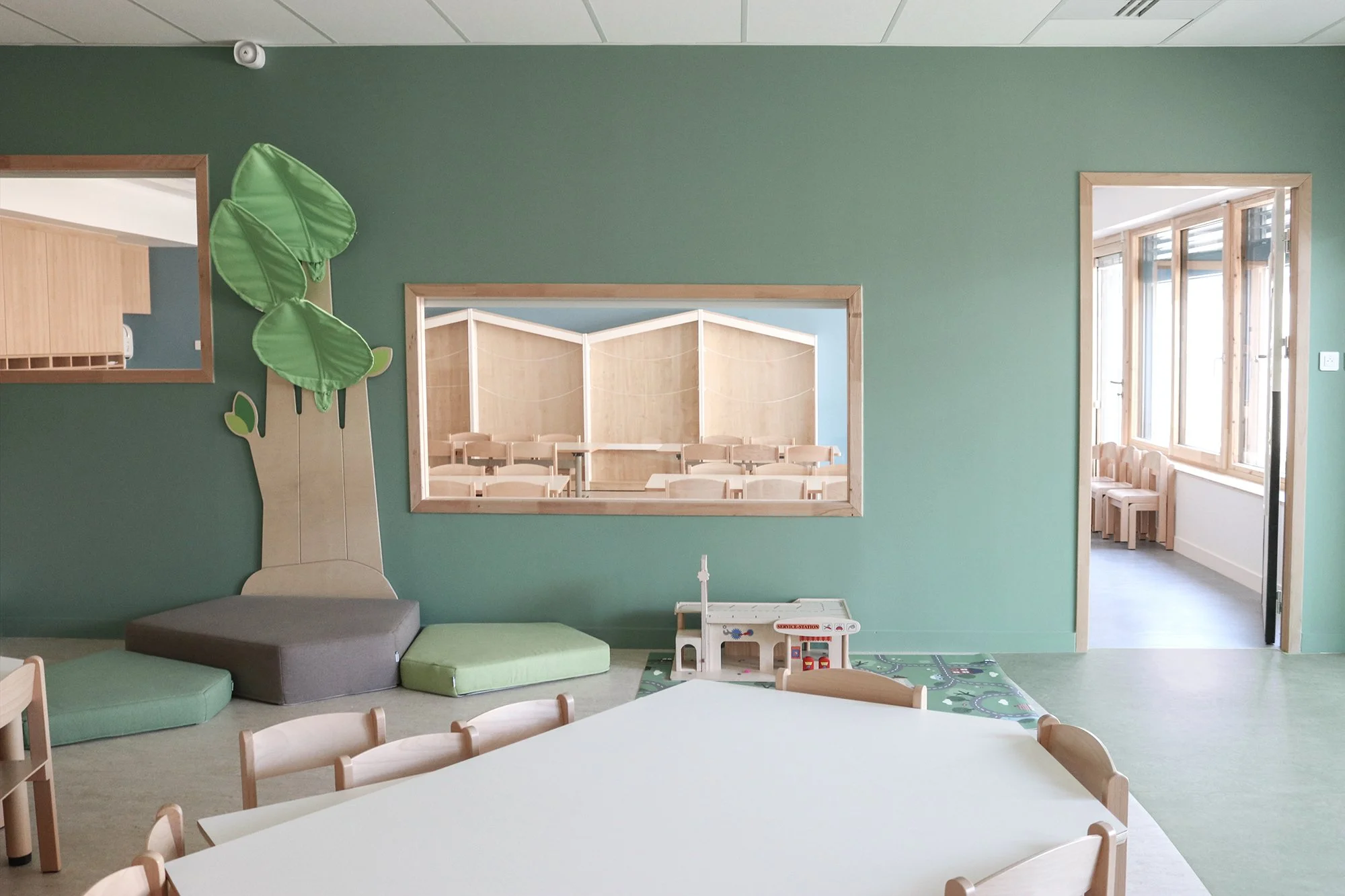 Salle d'activités, mur vert et mobilier petite enfance en bois, espace périscolaire et RPE du Pôle enfance jeunesse de Champagne-au-mont-d'or