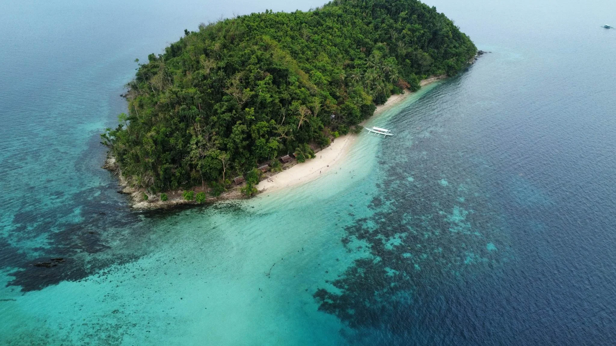 Aerial view of a tropical island with lush greenery, a sandy beach, and turquoise waters.