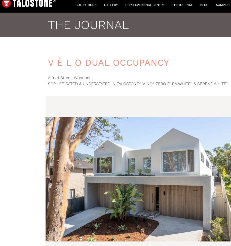 Modern white residential house with large windows, surrounded by greenery and trees, under a clear blue sky.
