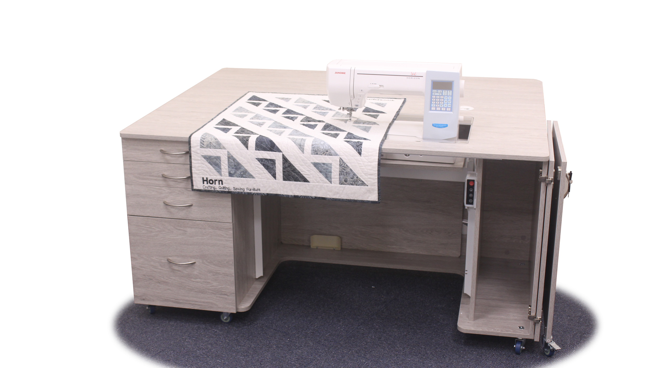 A sewing machine stitching a quilted fabric on a wooden desk with drawers, placed on a black circular rug.