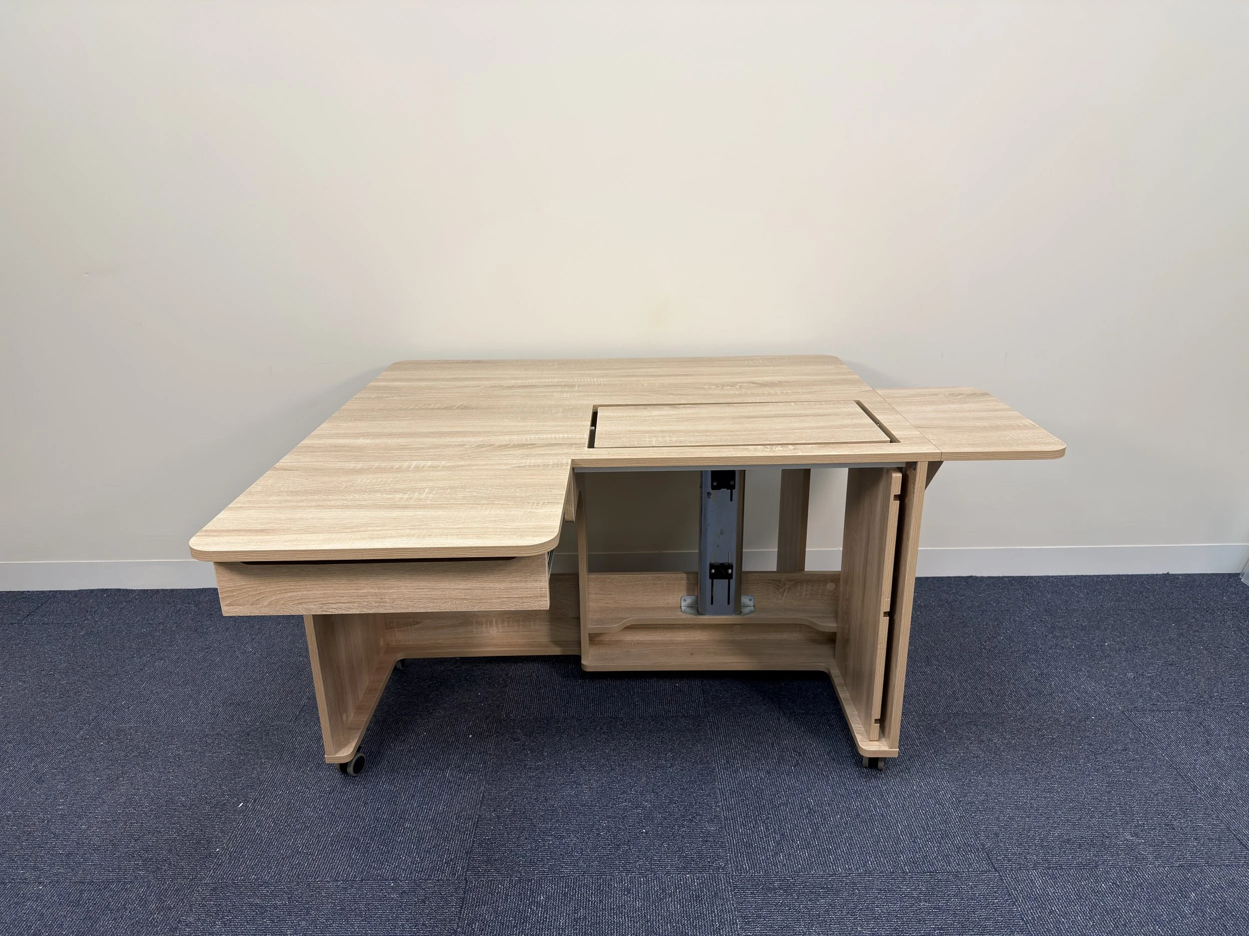 Wooden L-shaped desk with cutouts and wheels, placed against a white wall on a dark blue carpeted floor.