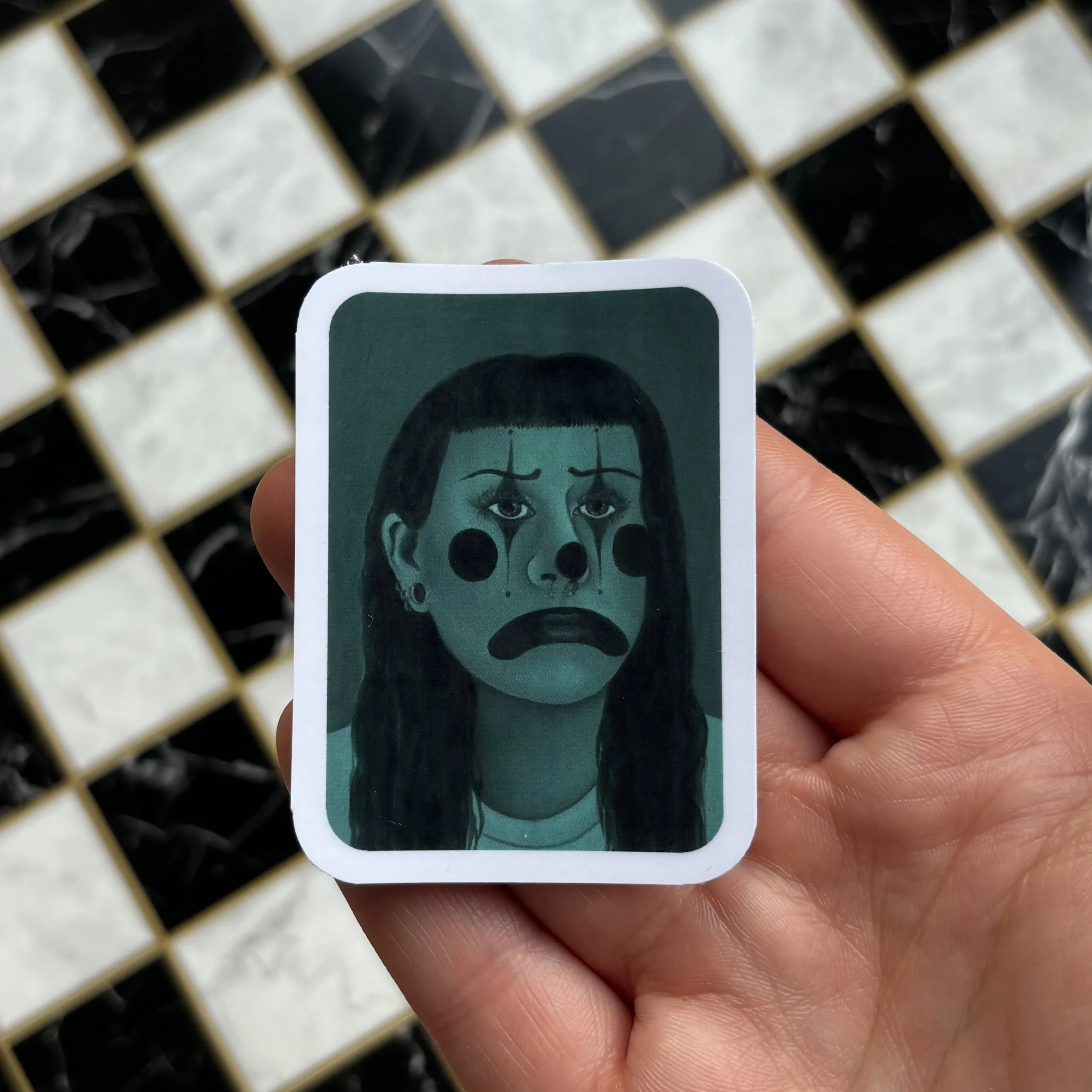 green clown sticker holding over checkerboard.jpg
