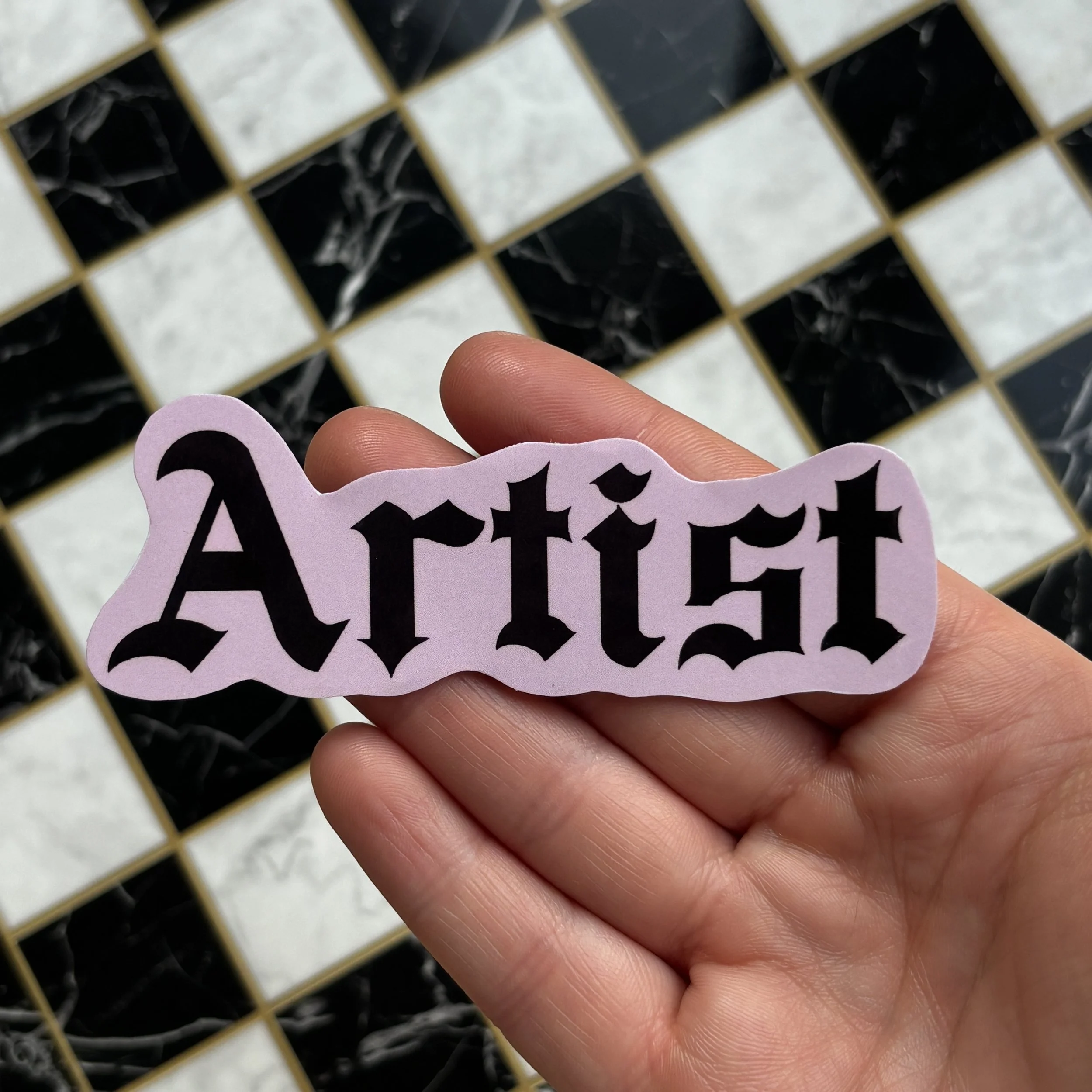 artist sticker holding over checkerboard.jpg