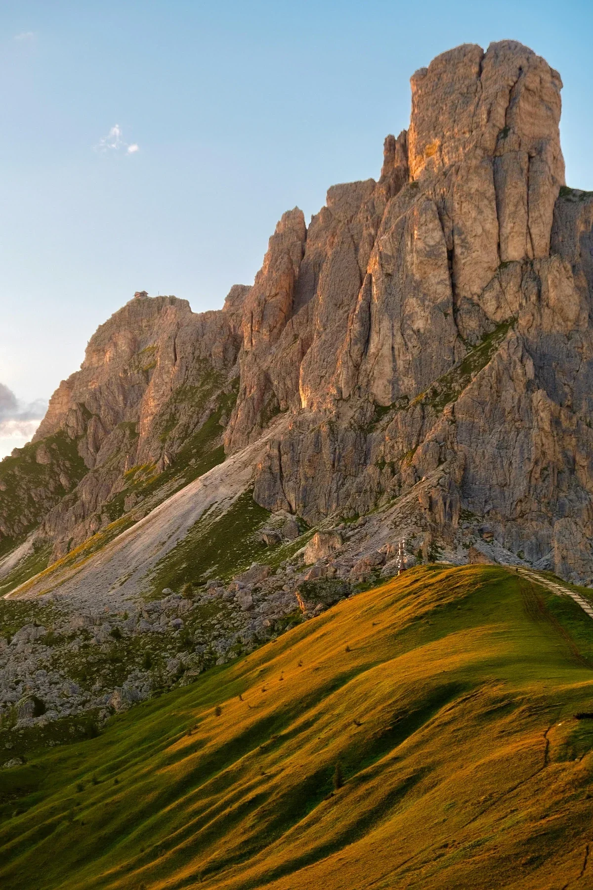  Sunlit Dolomite rock formations glowing at sunset with soft alpine terrain below. 