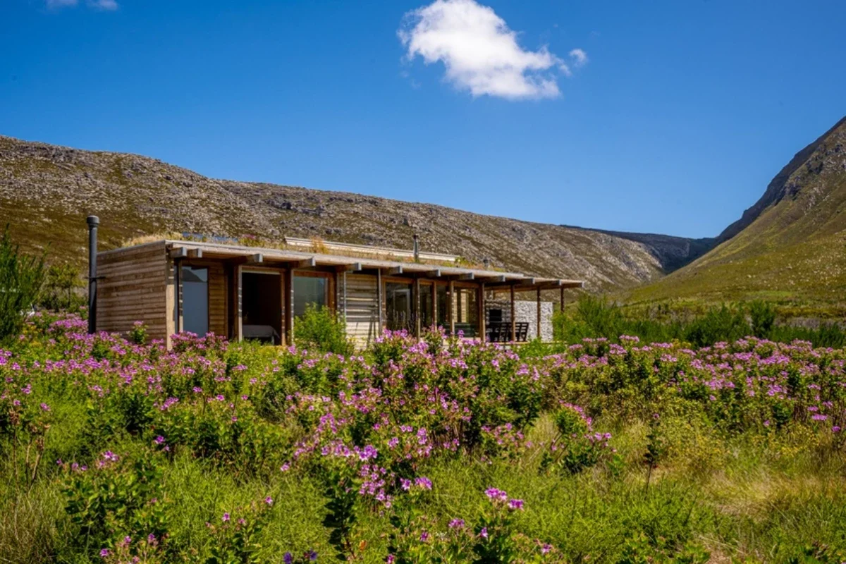 Outdoor deck at Oude Bosch eco cabin in Cape Town with seating area immersed in indigenous fynbos landscape.