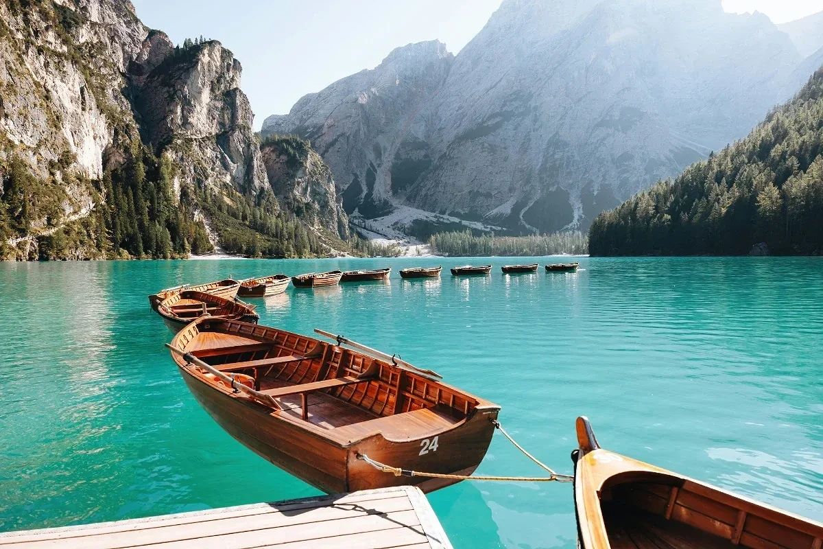  Wooden rowboats on Lago di Braies with turquoise water and mountain backdrop. 