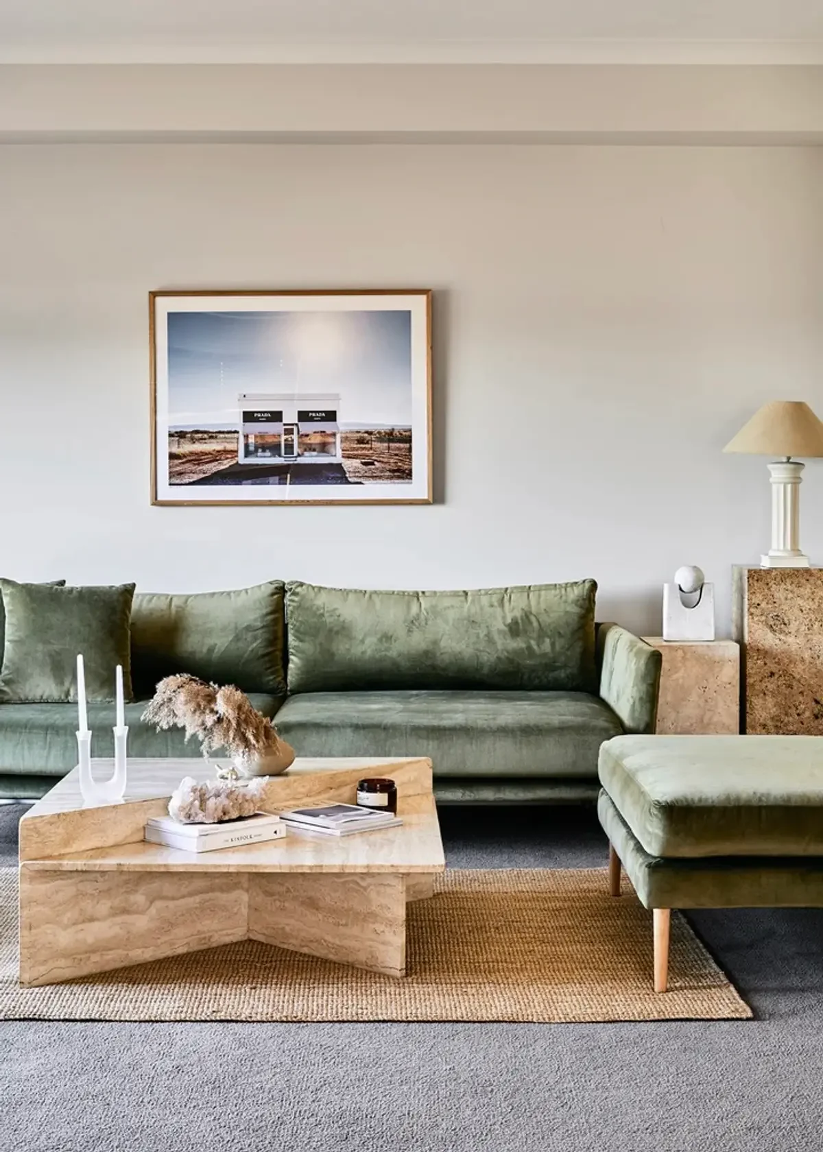 Contemporary lounge featuring a green velvet sofa and a travertine X-base coffee table.