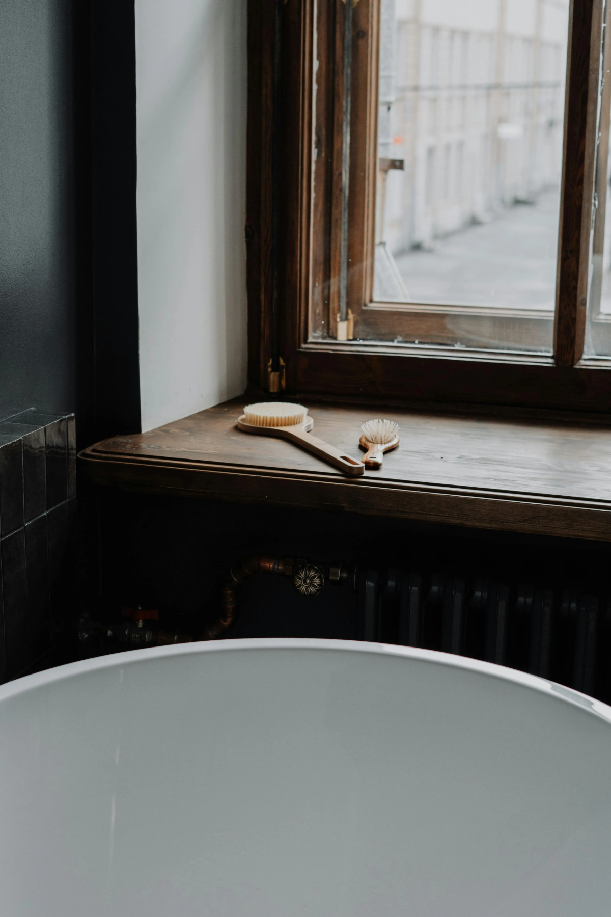 Two wooden body brushes rest on a rustic windowsill.