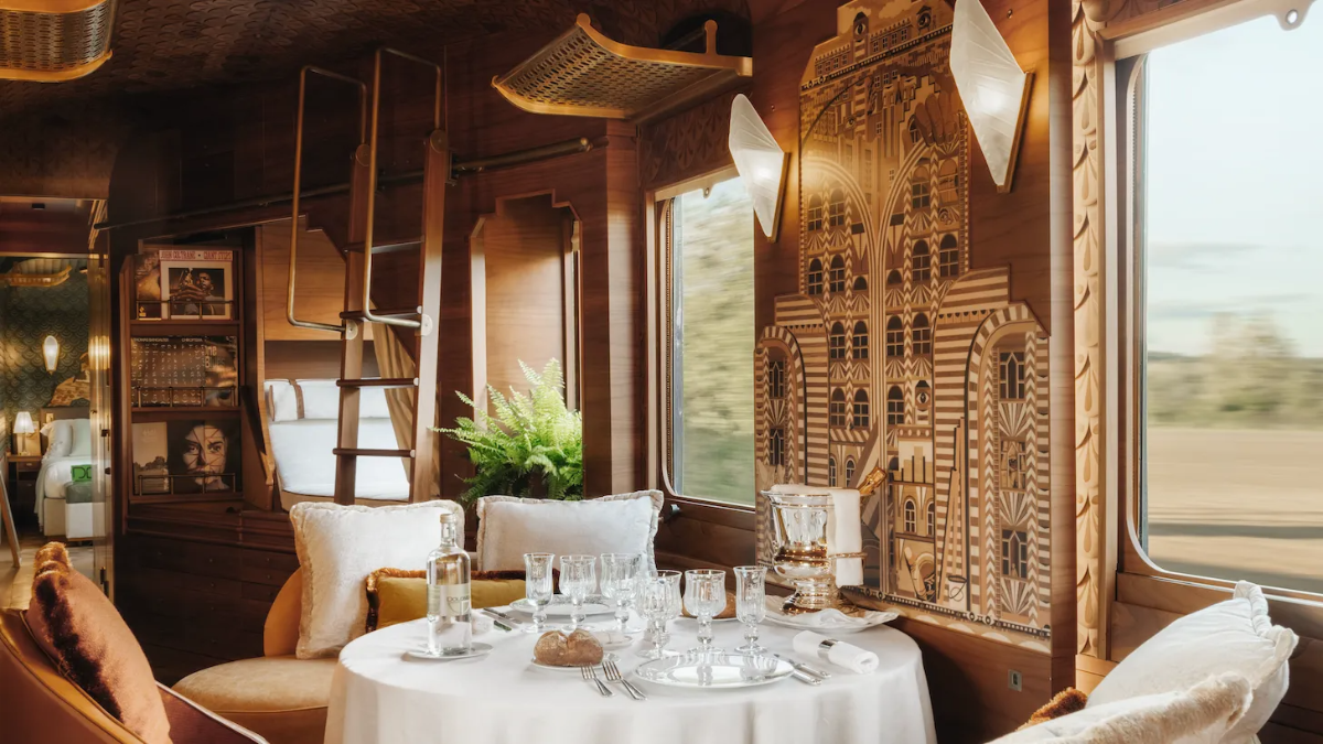 Art-deco luxury Orient Express train suite, wood paneling and landscape rushing past the window (concept image, not Orient Express Corinthian).
