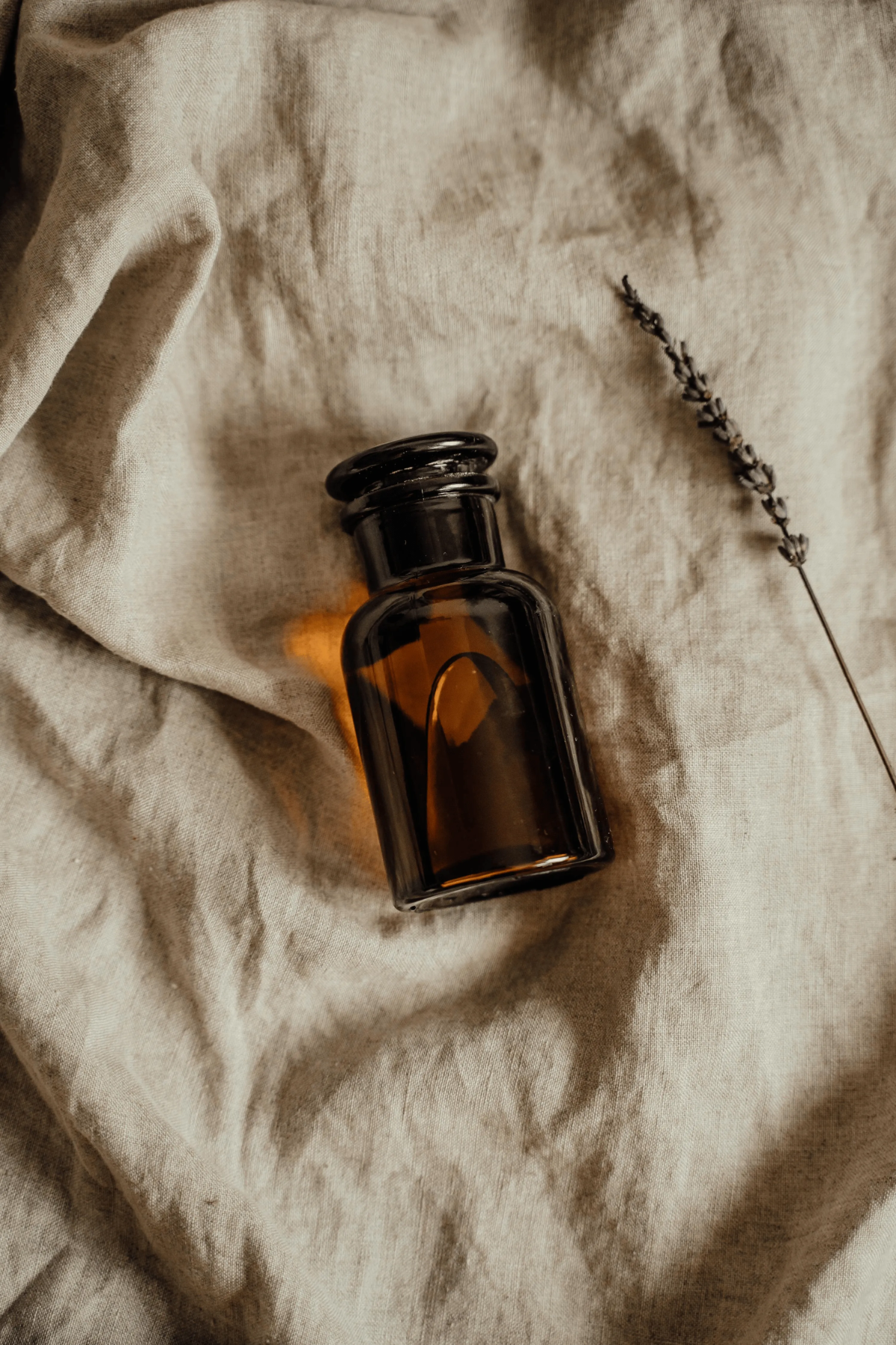 Amber apothecary bottle on rumpled linen cloth.