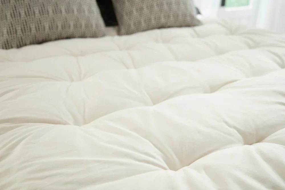  Lofty natural wool topper by PlushBeds, tufted for cloud-like comfort. 