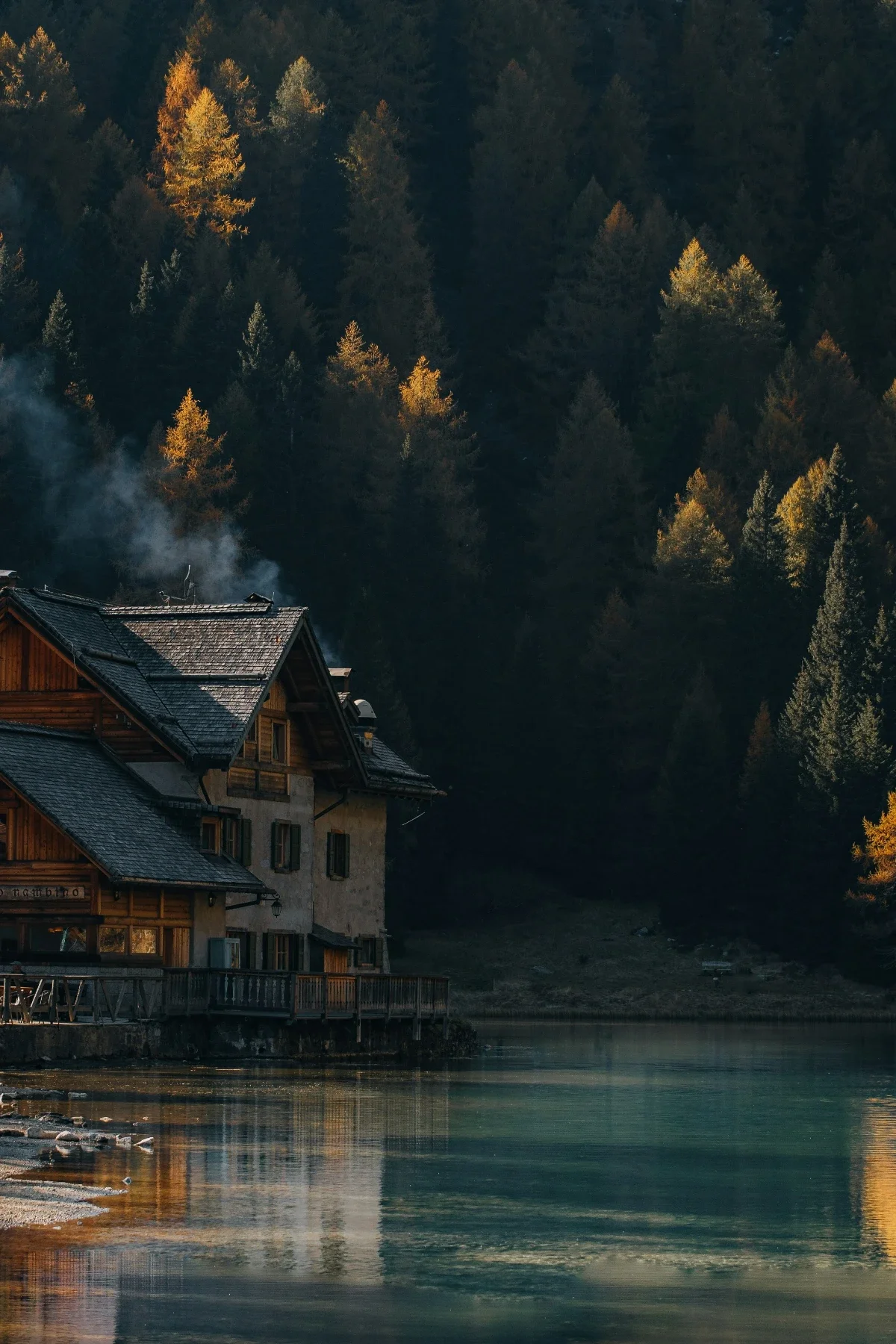  Wooden cabin on Lago di Braies with calm water and forest reflections in autumn light. 