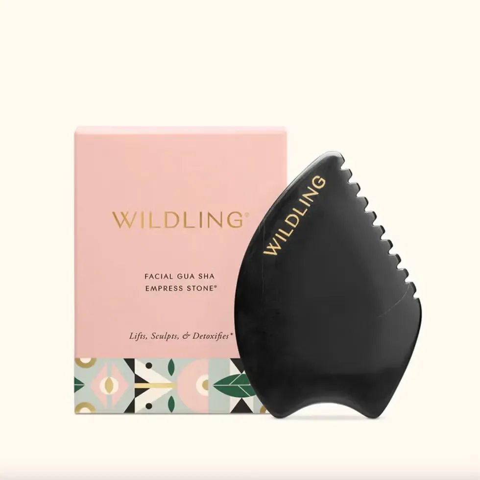 Wildling black Empress Stone gua sha tool next to its pink box.