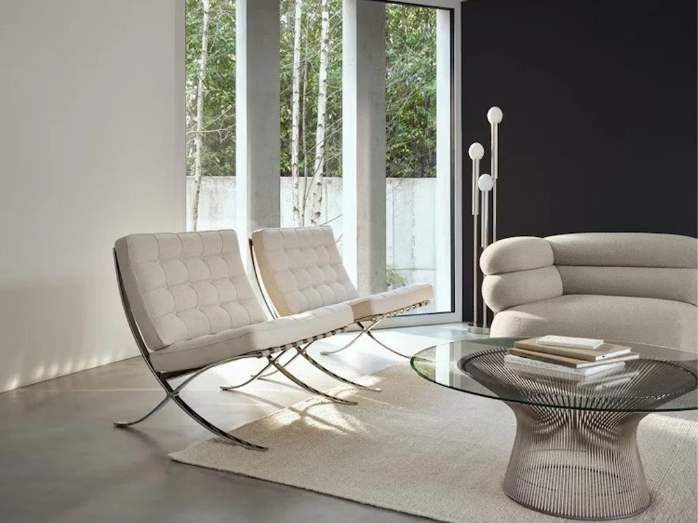 Living room with ivory Barcelona chairs, glass Platner coffee table and neutral sofa.