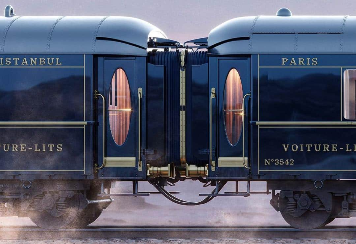Midnight-blue Orient Express sleeper carriages with brass trim and oval windows, gentle steam drifting at dawn.