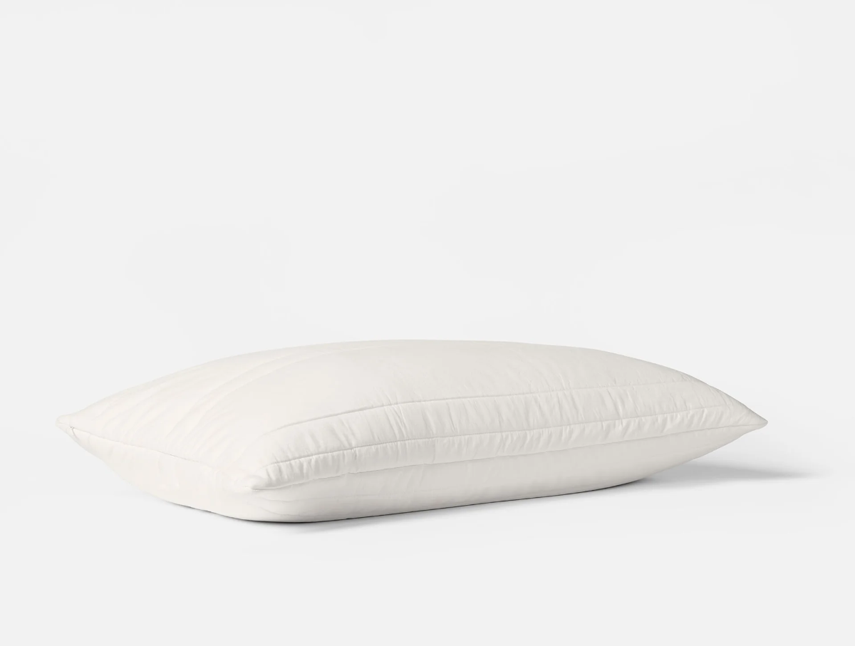 Coyuchi washable wool-filled pillow protector in soft white, shown side profile on seamless white background.