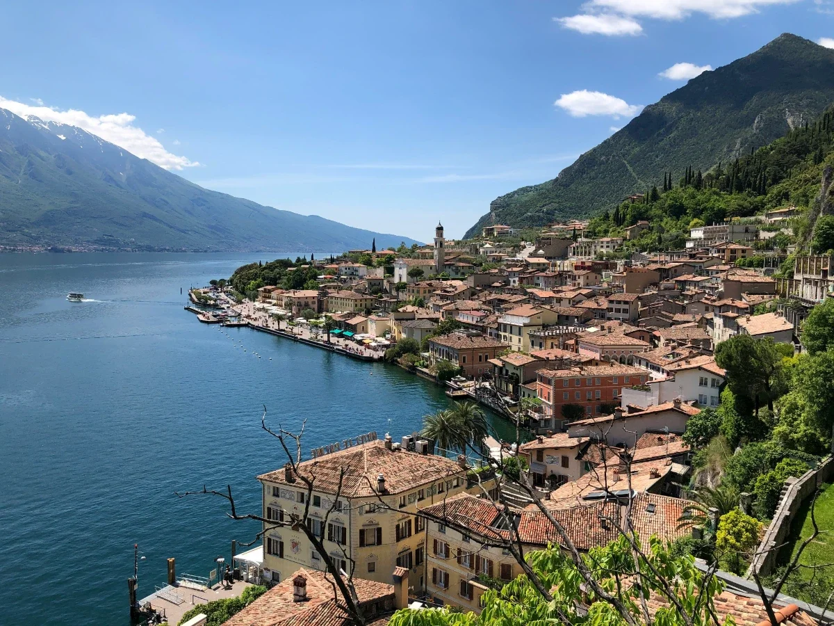 Scenic lakeside town with terracotta roofs and bell tower along deep-blue Lake Garda backed by alpine ridges.