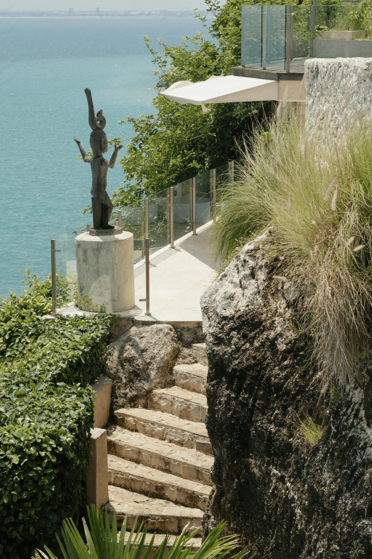 Stone steps carved into cliff overlooking turquoise ocean.