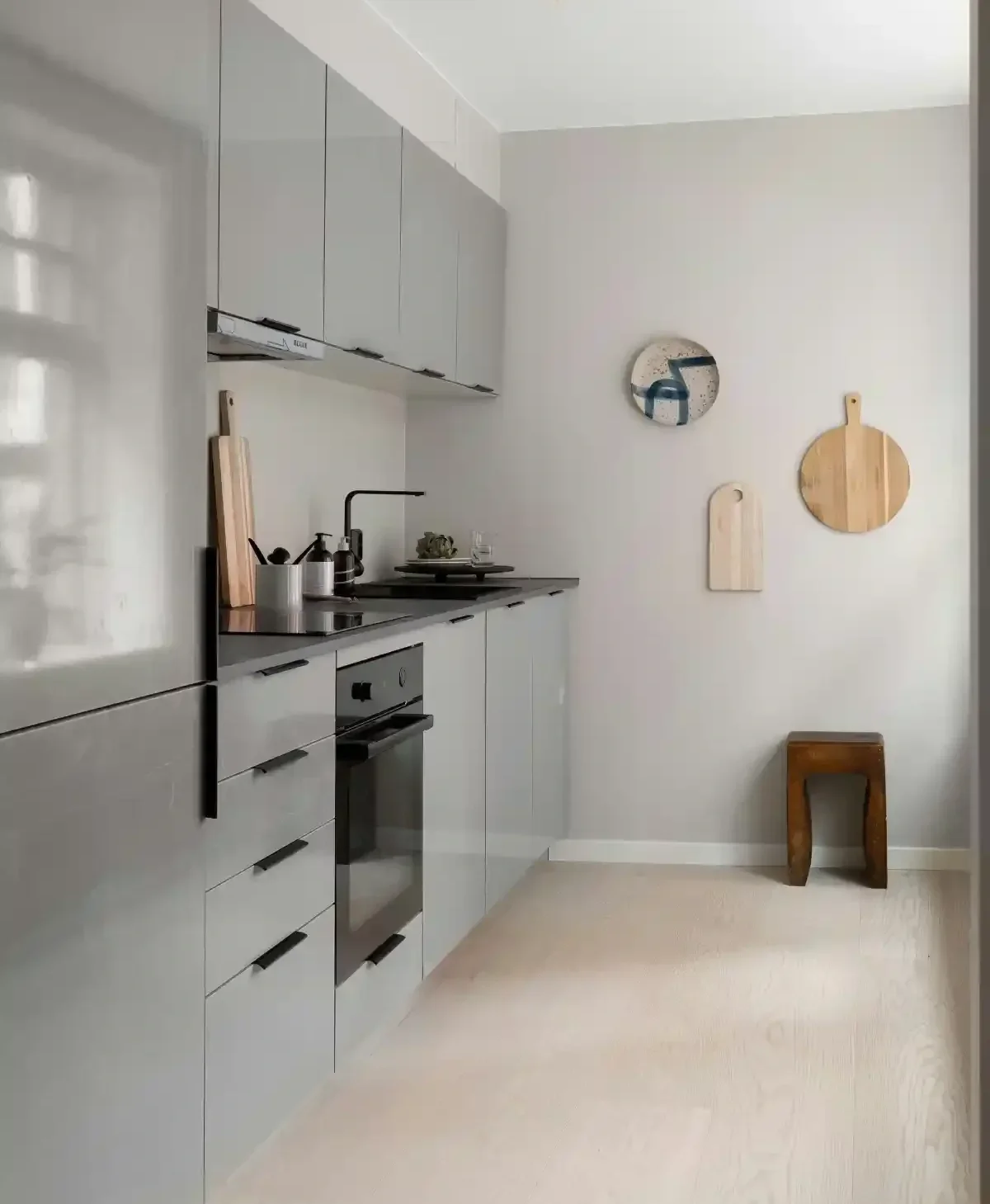 Slim grey galley kitchen with black hardware and black-top counters.