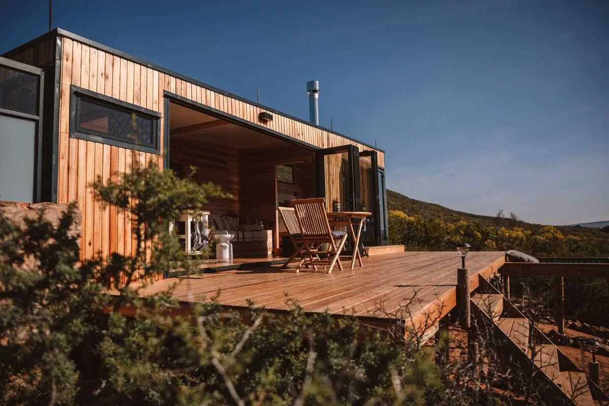 Off-grid cabin at Solace Rawsonville set against rugged terrain and open sky in a remote wine valley region.