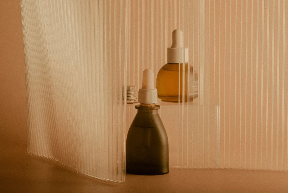 Two dropper bottles in front of a curved translucent panel.