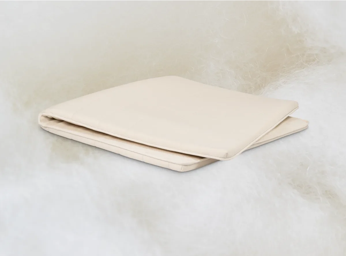  Folded Birch organic wool mattress topper resting on a fluffy wool backdrop. 