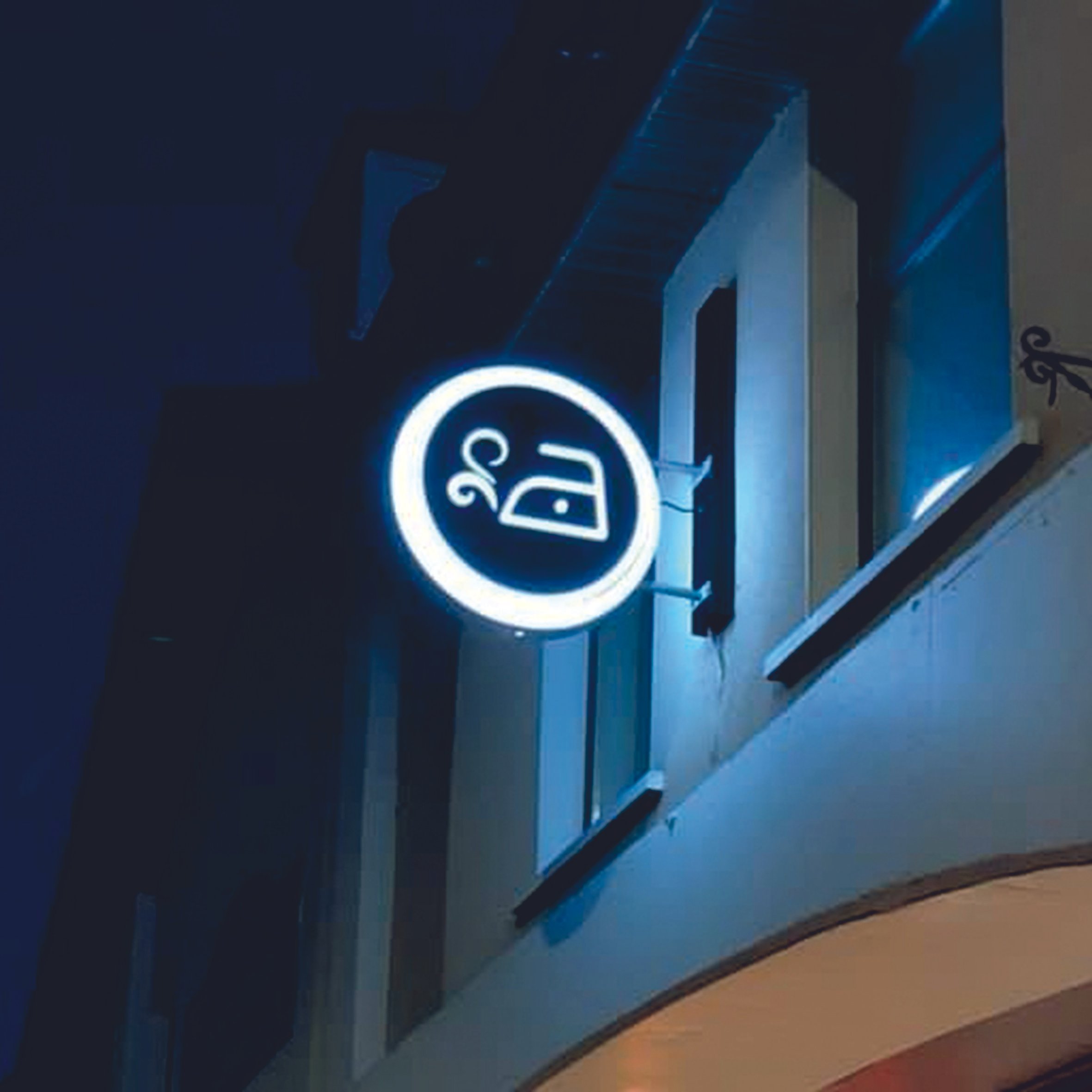 Illuminated circular sign with an iron symbol at night. Projecting sign. Raised LED Letters. Illuminated signage. Signmakers Cork & Kerry, Ireland.