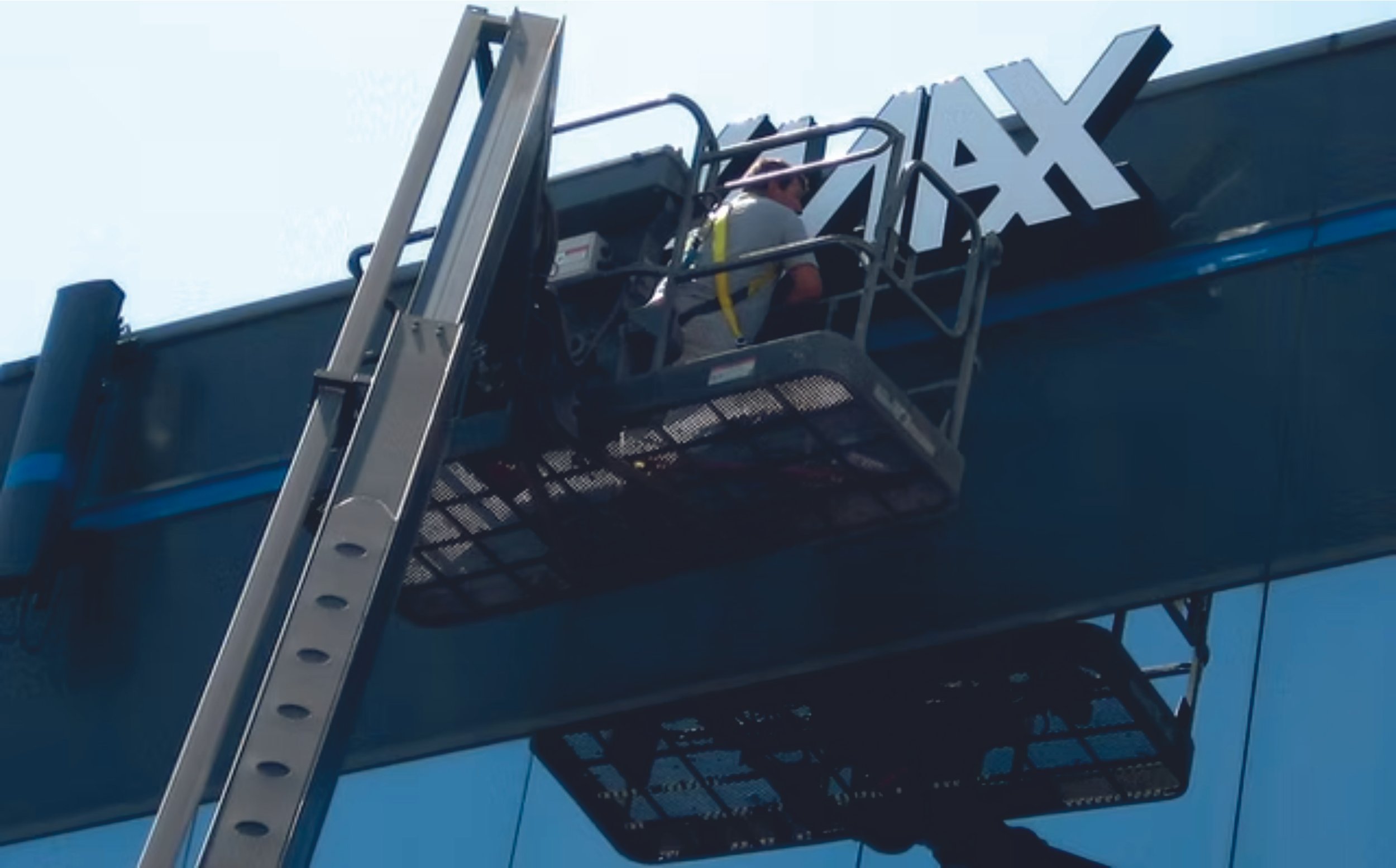 Worker on a lift installing large letters on a building sign. Signmakers Cork & Kerry, Ireland.