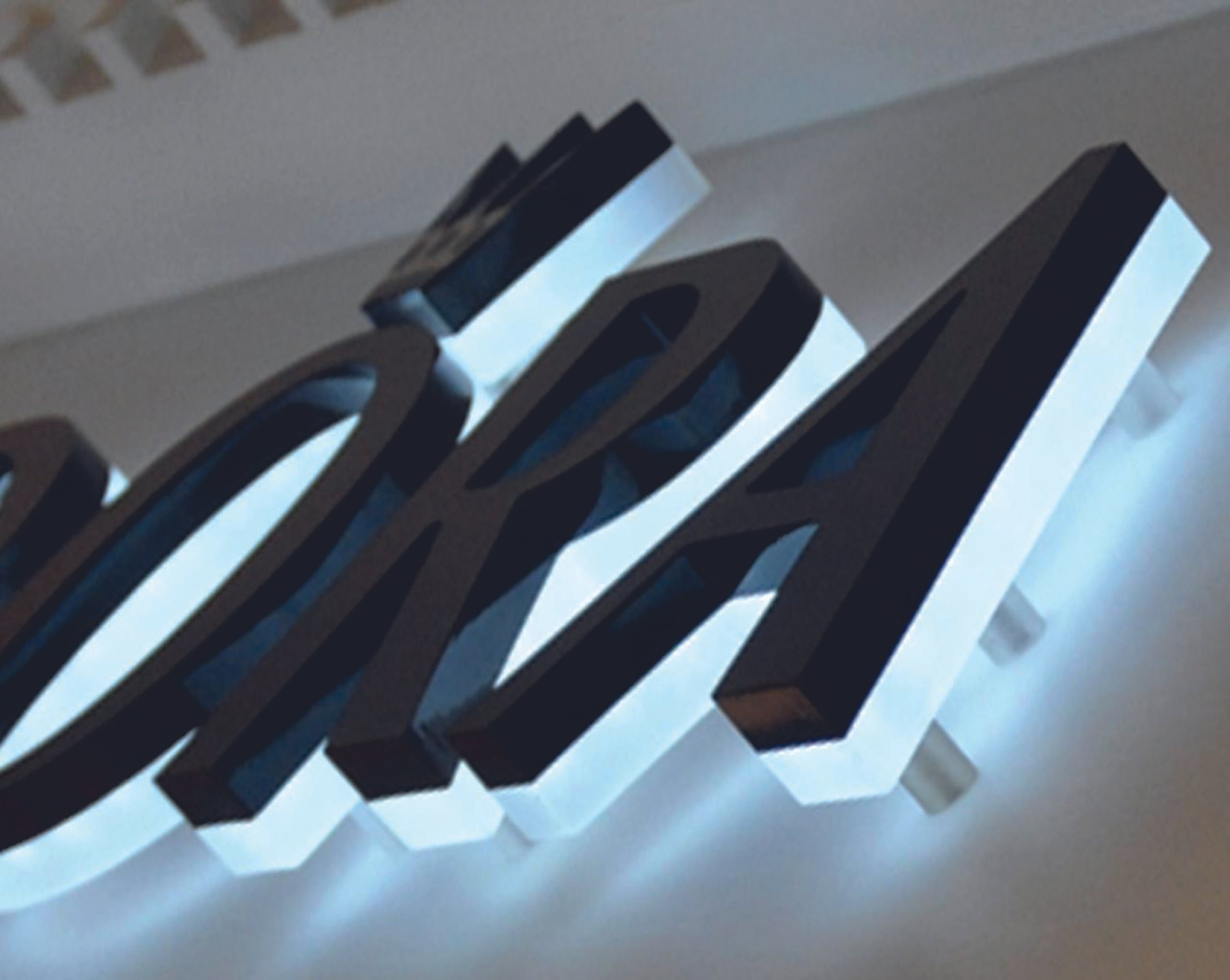Close-up of illuminated black sign letters on a wall. Raised LED Letters. Illuminated signage. Signmakers Cork & Kerry, Ireland.