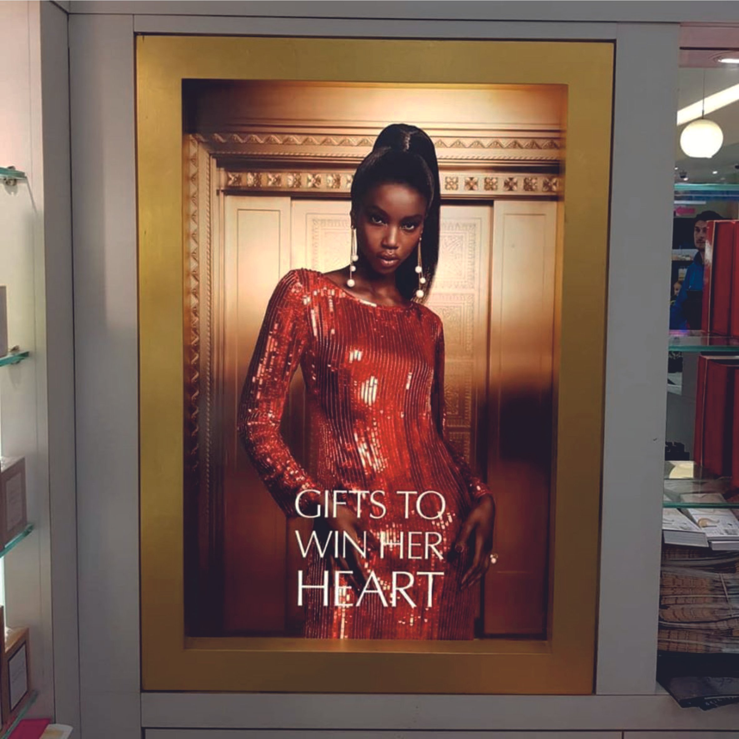 Fashion advertisement with model in red dress and text "Gifts to Win Her Heart". Raised LED Letters. Illuminated signage. Signmakers Cork & Kerry, Ireland.