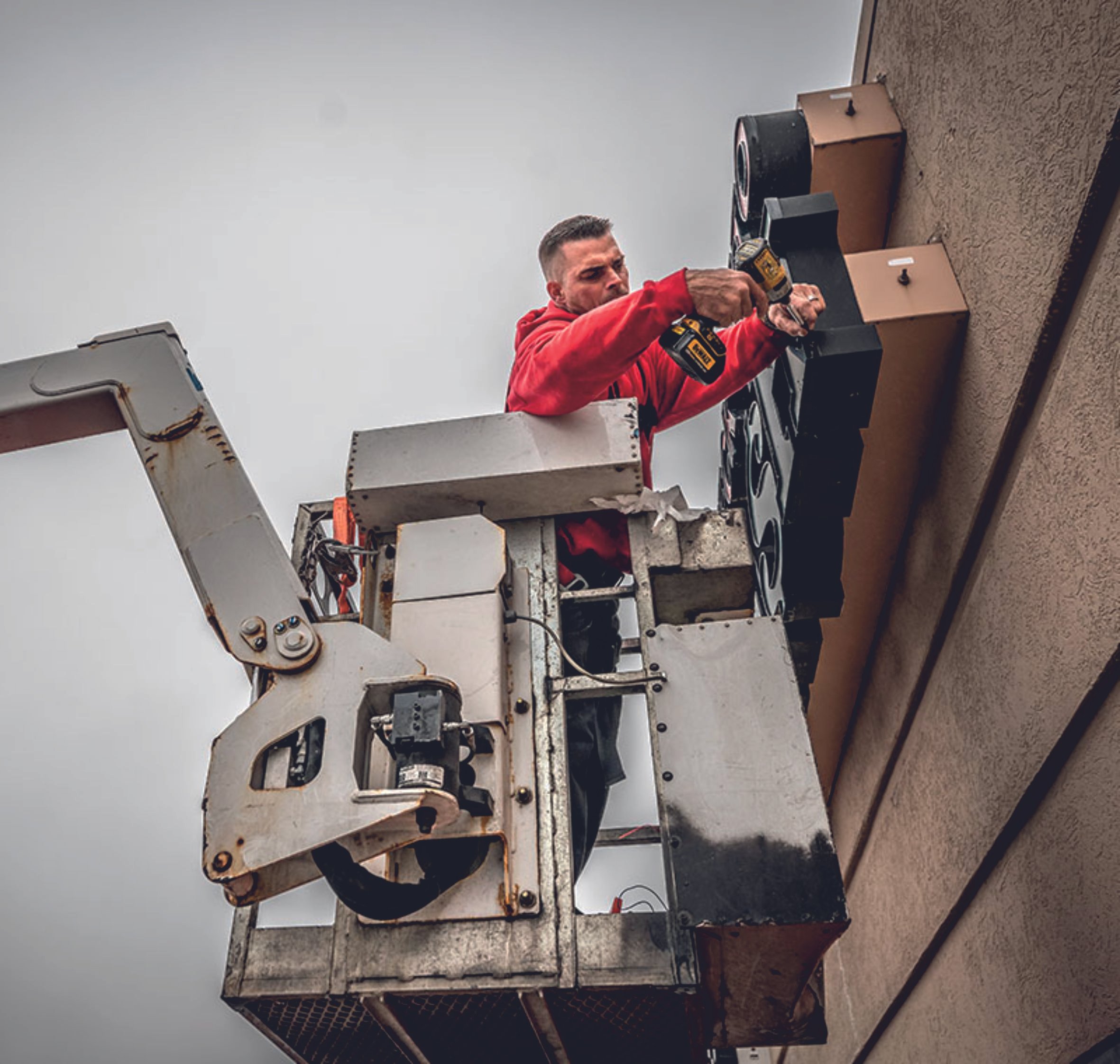 Worker on a lift installing or repairing a sign on a building. Signmakers Cork & Kerry, Ireland.