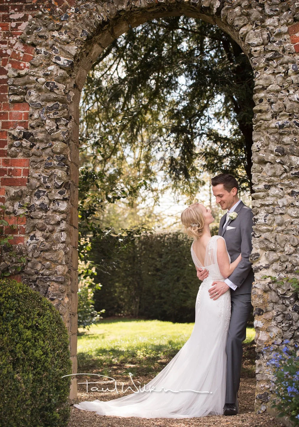 A wedding couple beneath a stone arch at Hampden House