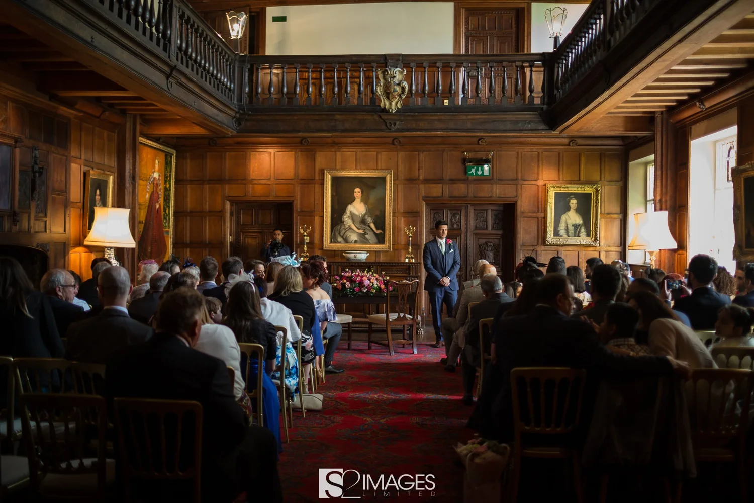The Great Hall with wood panelling, paintings and upper gallery, shown set for a ceremony