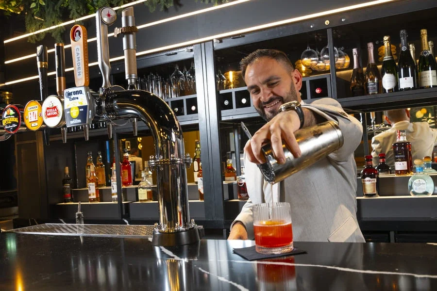 Our restaurant manager prepares a cocktail at The Engine Room, smiling broadly