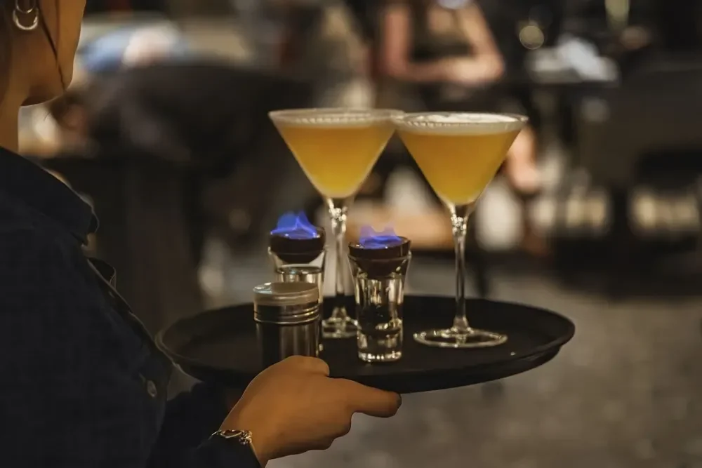 Close up of a tray being carried with two martinis and two flaming cocktails at The Engine Room in Derby