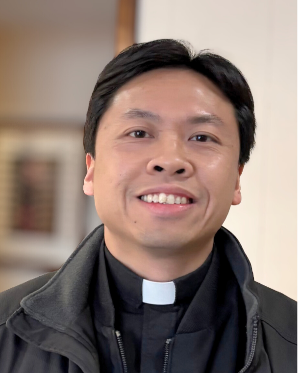 A smiling Fr. Trieu Hai Hoang, standing in side the office of St. Albert the Great Campus