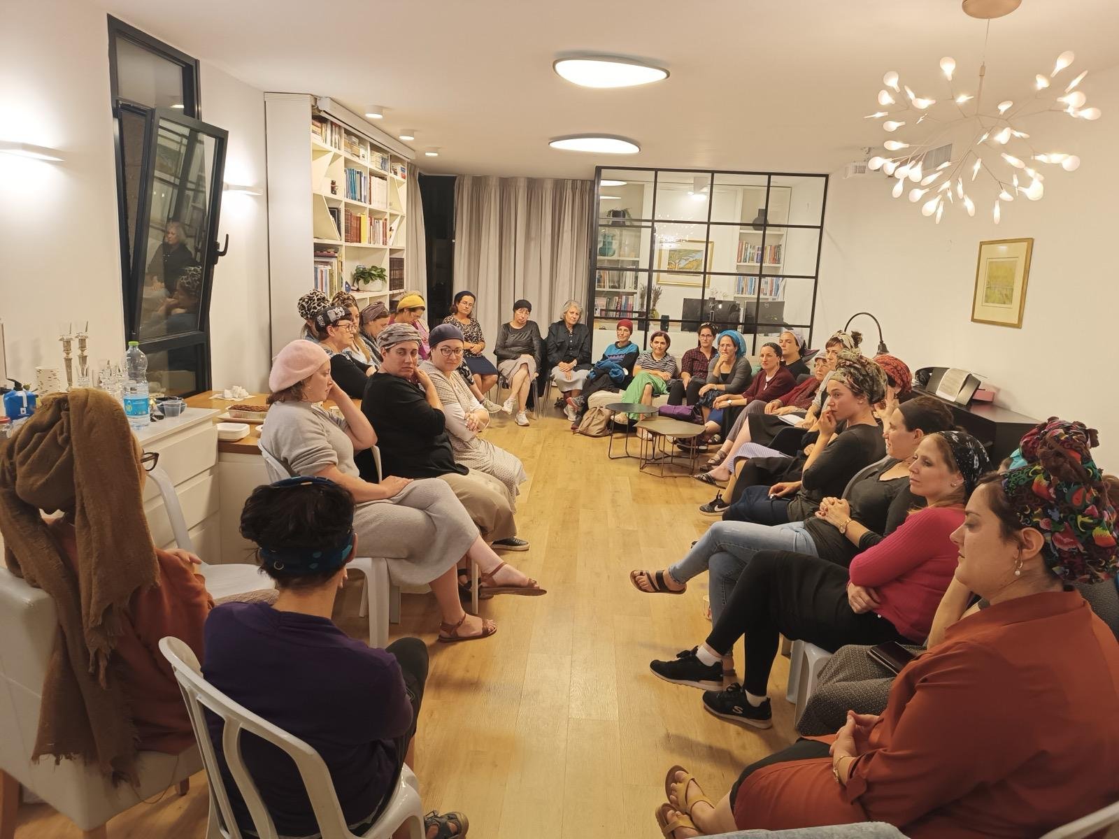 A group of people sitting in a living room, engaged in a discussion.