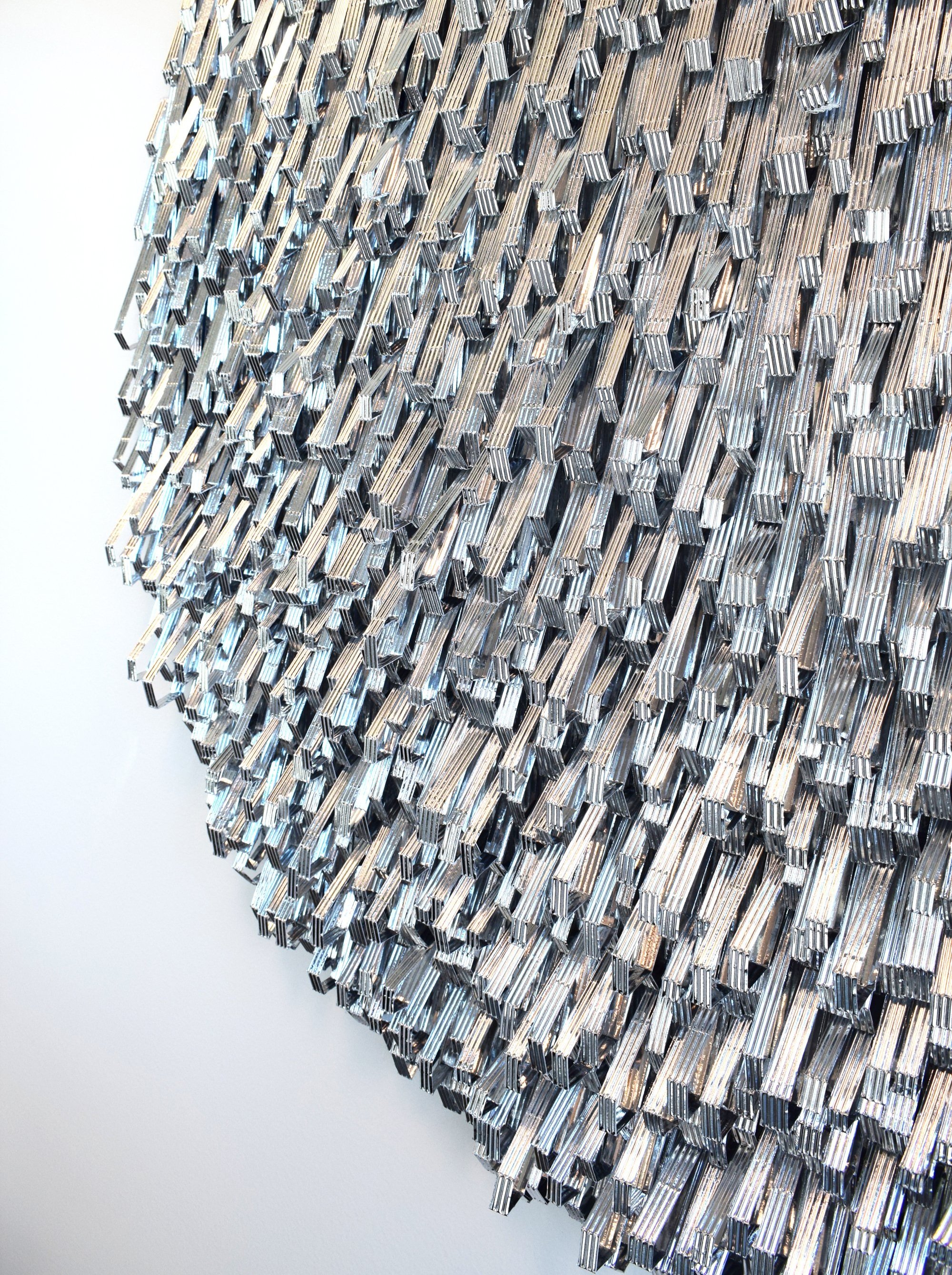 Close-up of a large metallic sculpture made of numerous elongated, shiny metal rods arranged densely and in an abstract pattern.