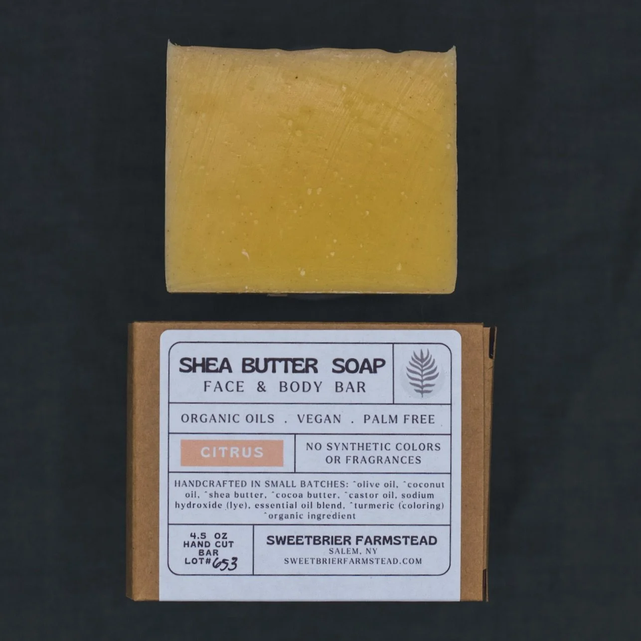 2 bars of Sweetbrier Farmstead natural Citrus Bar Soap one in packaging on green background