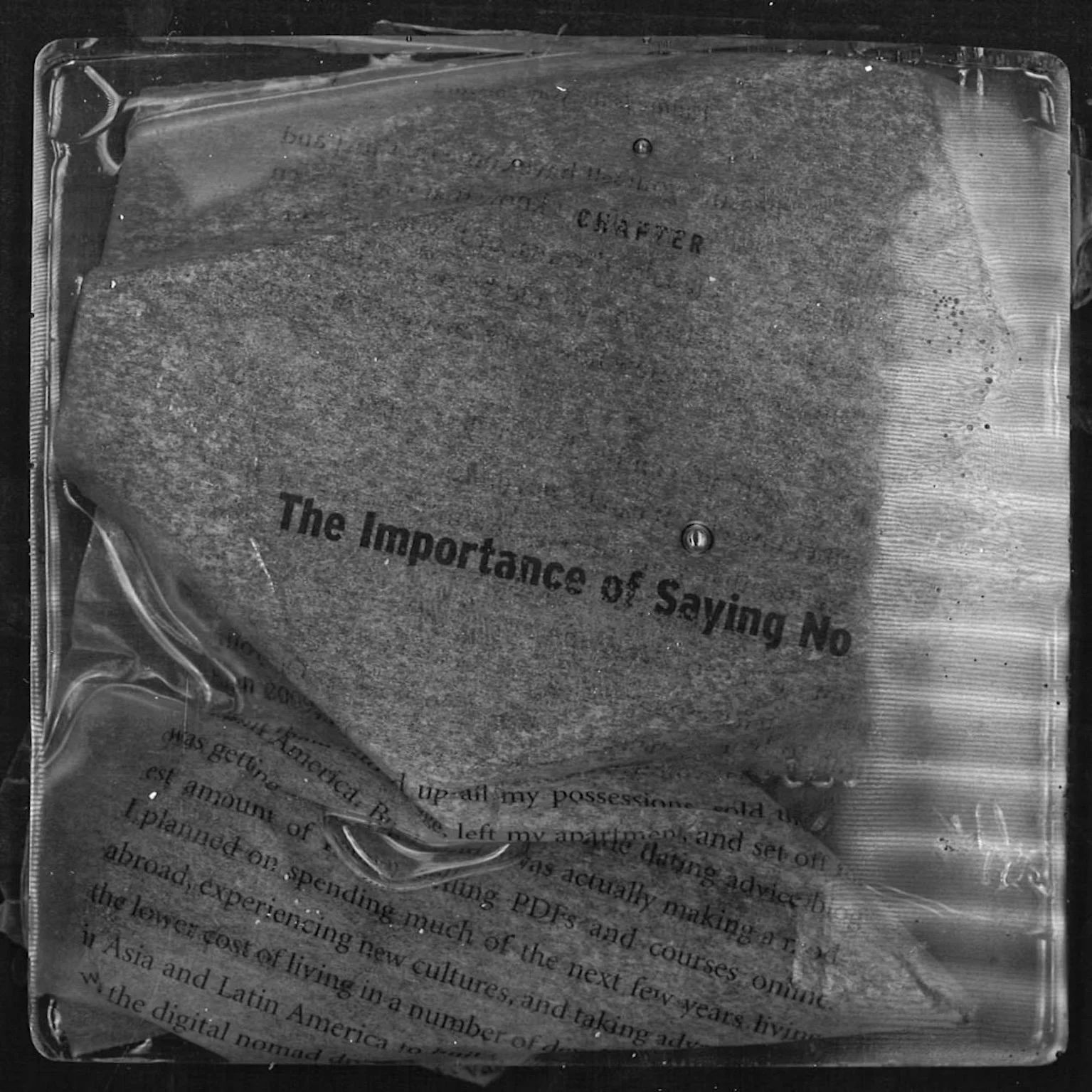 Close-up of a book page with the title 'The Importance of Saying No' partially visible, under a clear plastic sheet.
